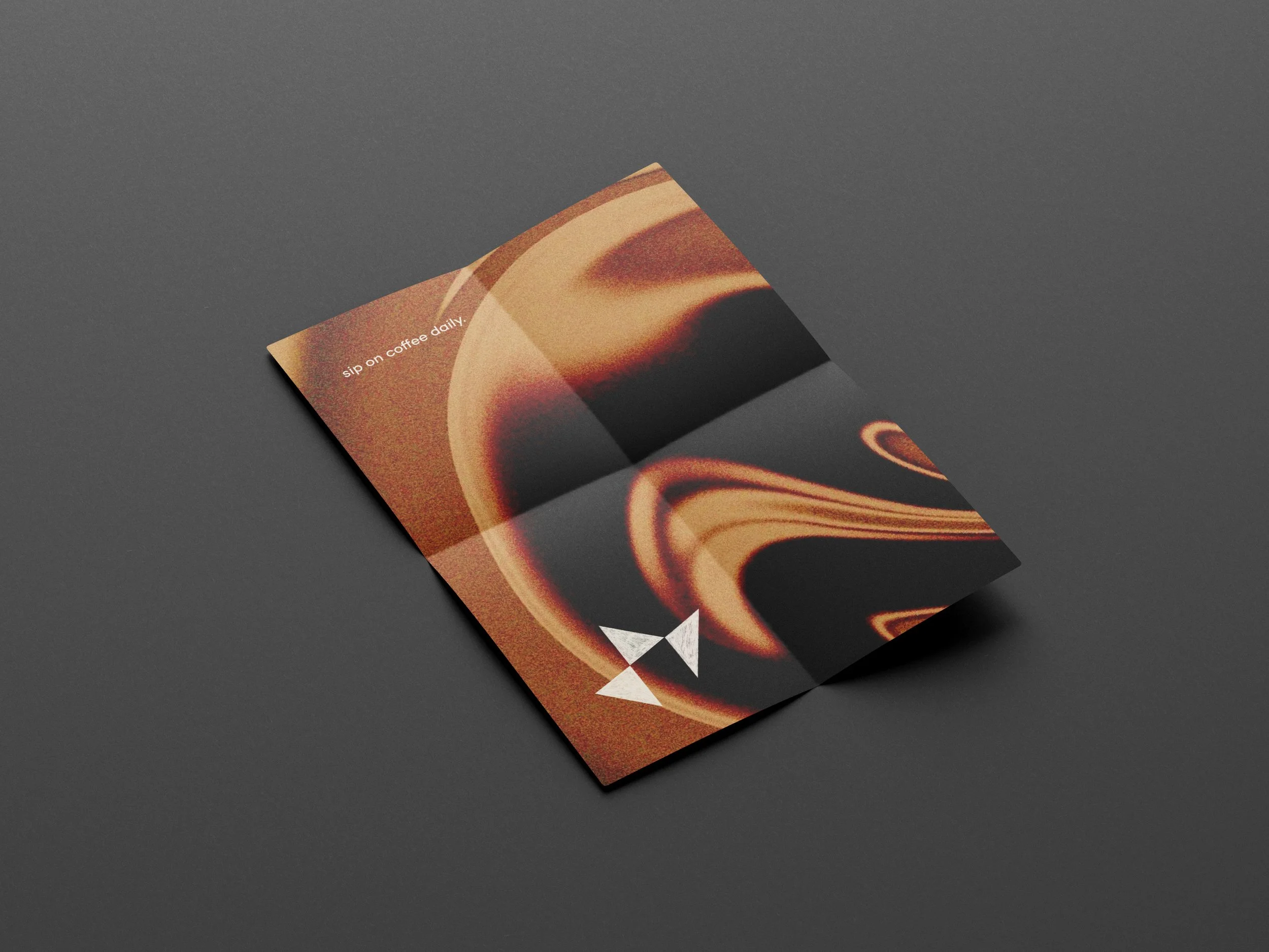 Close-up of an open book with abstract, swirling patterns in warm tones, placed on a dark gray surface.