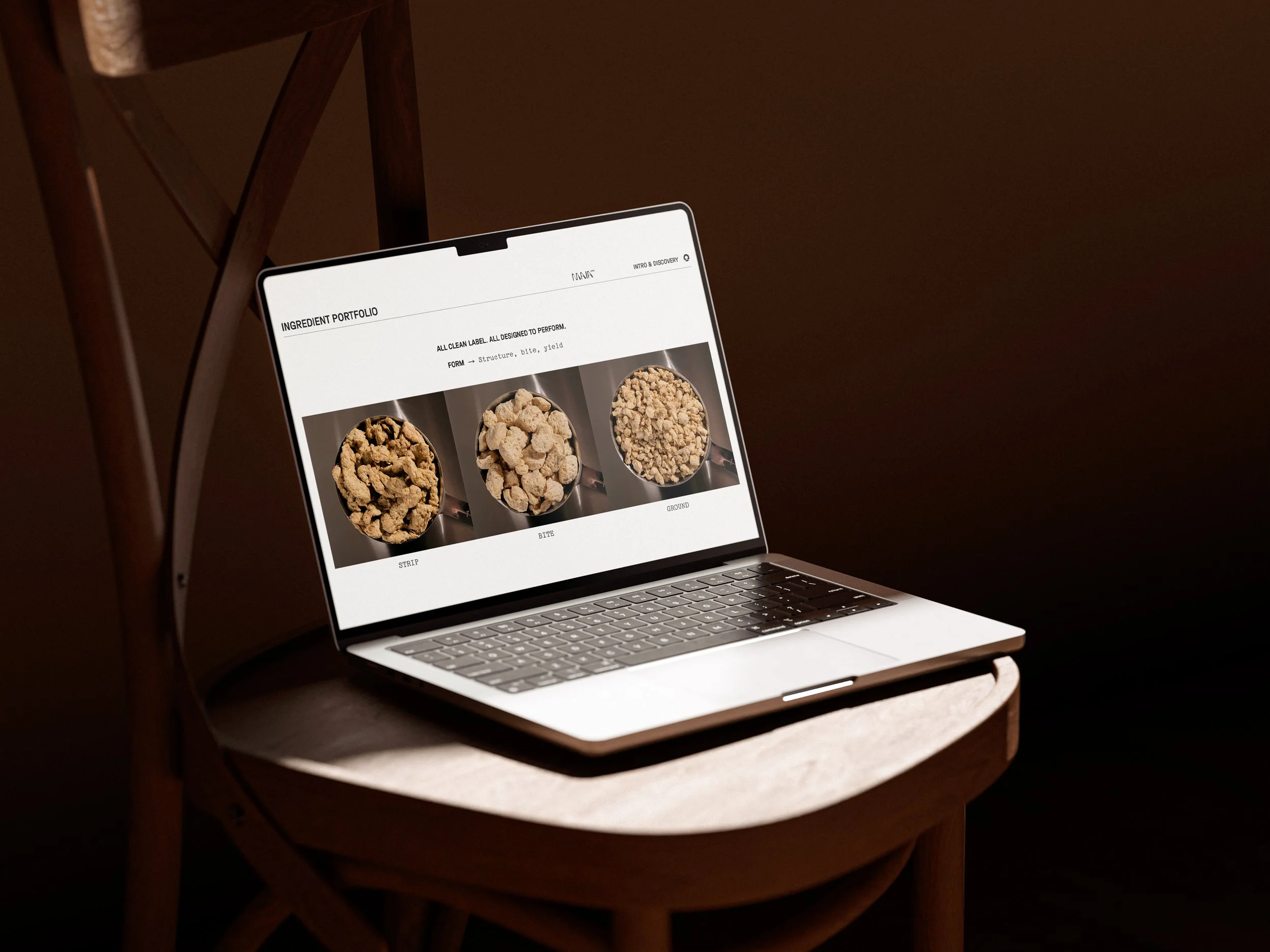A laptop open on a wooden table displaying a webpage about ingredient portfolio with images of mushroom powder and protein.
