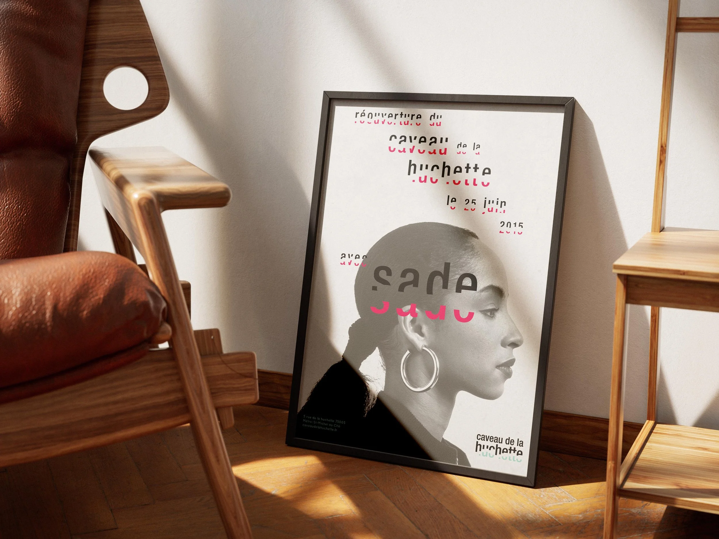 A framed poster leaning against a wall with a black and white profile image of a woman's head and neck. There are wooden chairs and a small wooden table nearby, with sunlight casting shadows on the wooden floor.