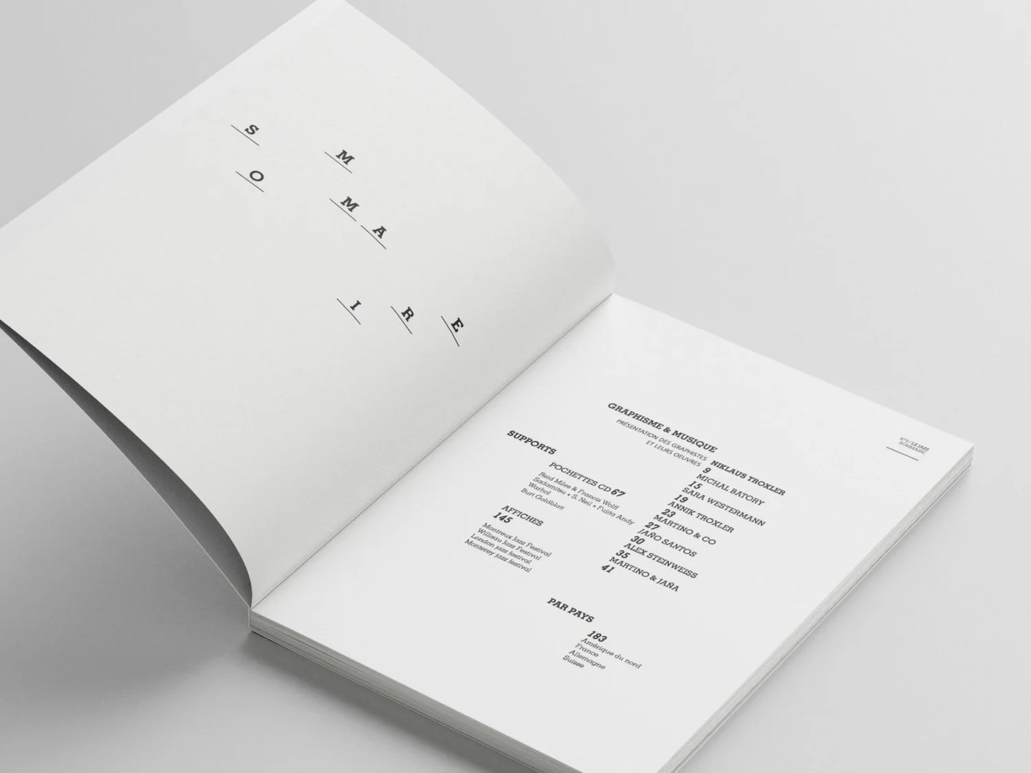 Open magazine with minimal black text on white pages, displaying a list of chapters with a large stylized text saying 'SOMAIRE' on the left page.