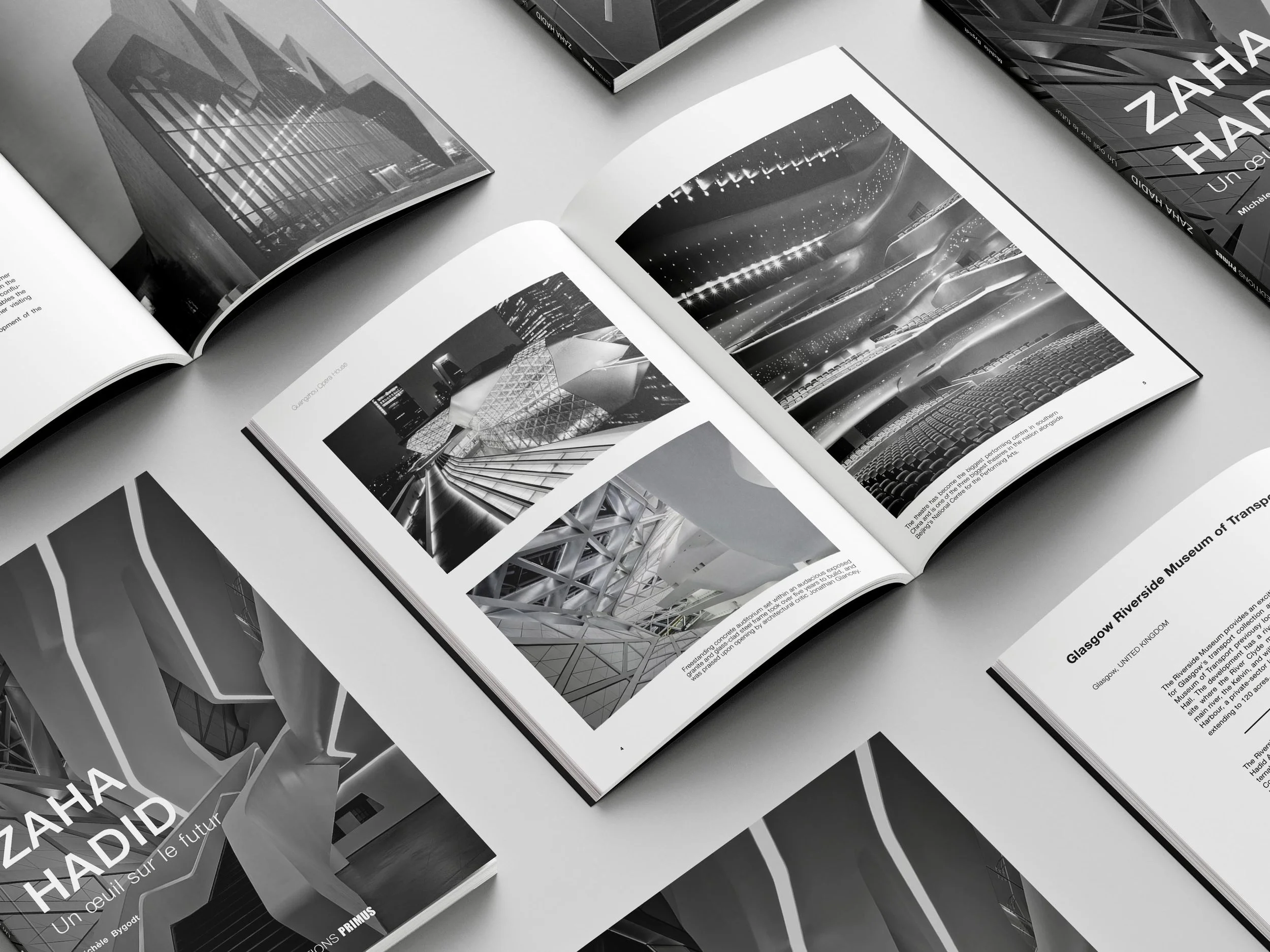 A collection of books and magazines, some open and some closed, featuring images of modern architecture and cityscapes in black and white, arranged on a surface.