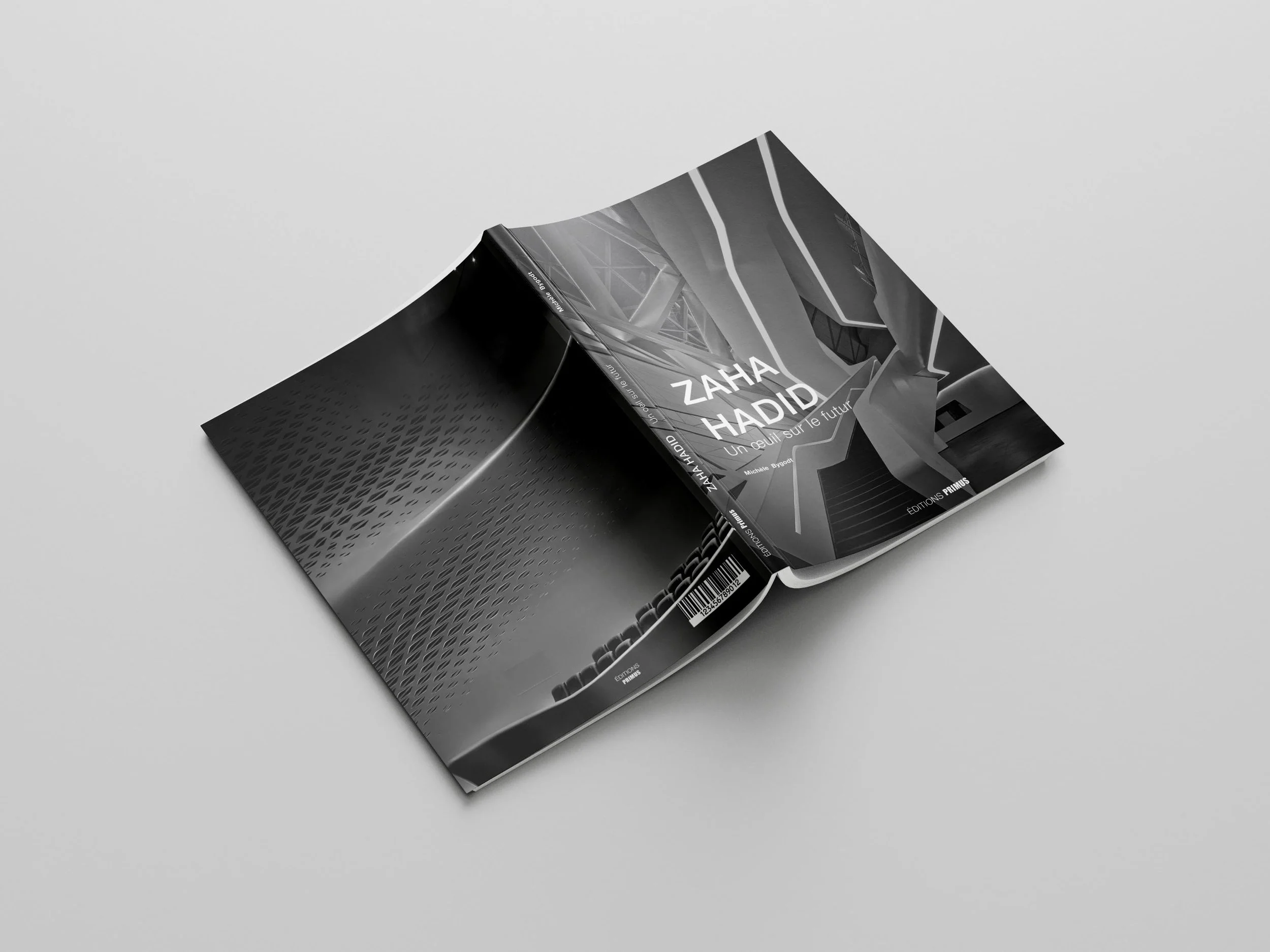 Black and white photograph of a book titled 'Zaha Hadid: Un œil sur le futur' lying partially open on a gray surface.