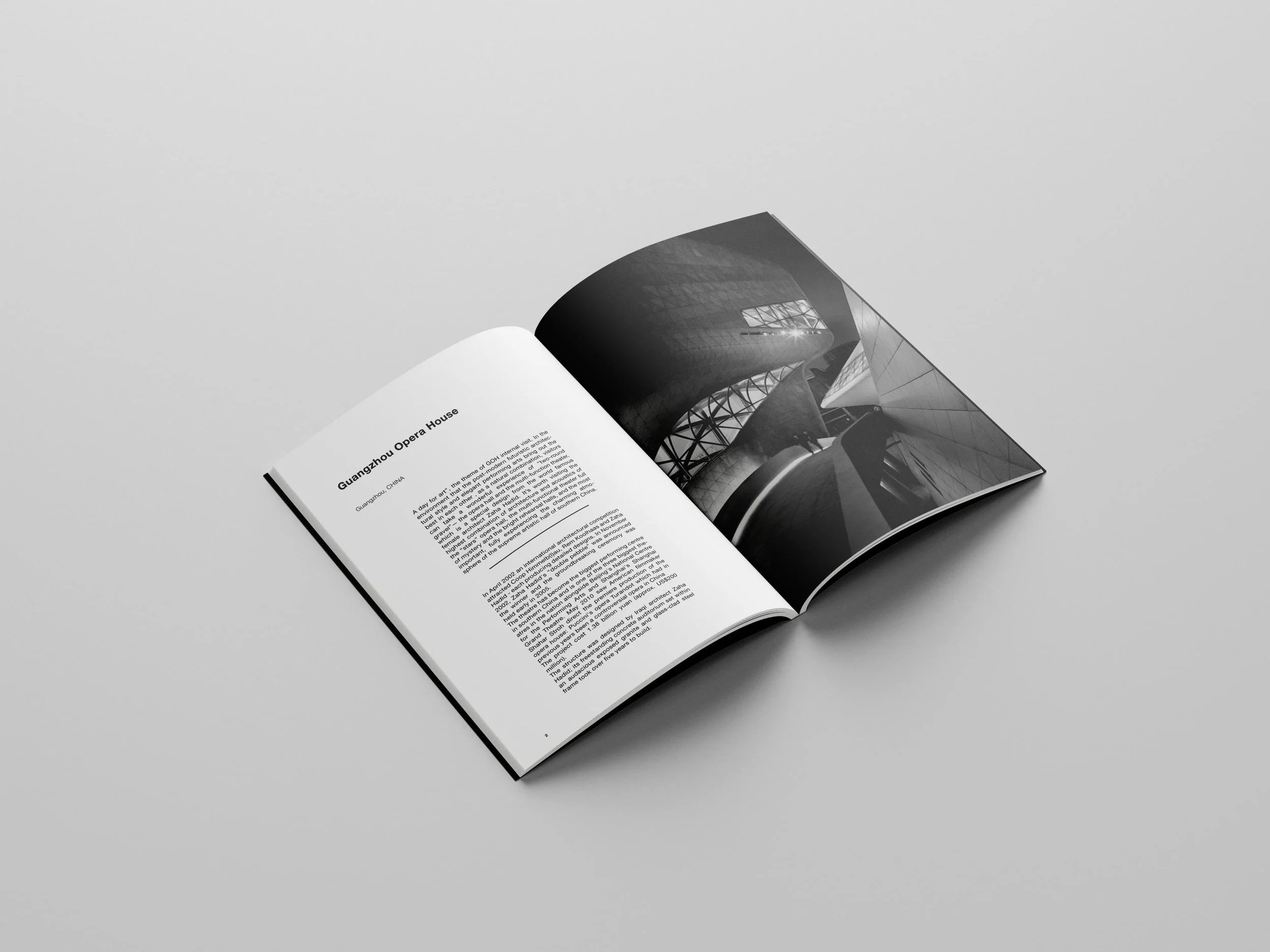 Open magazine or brochure on a plain gray surface, showing black-and-white photographs and text about Guangzhou Opera House.