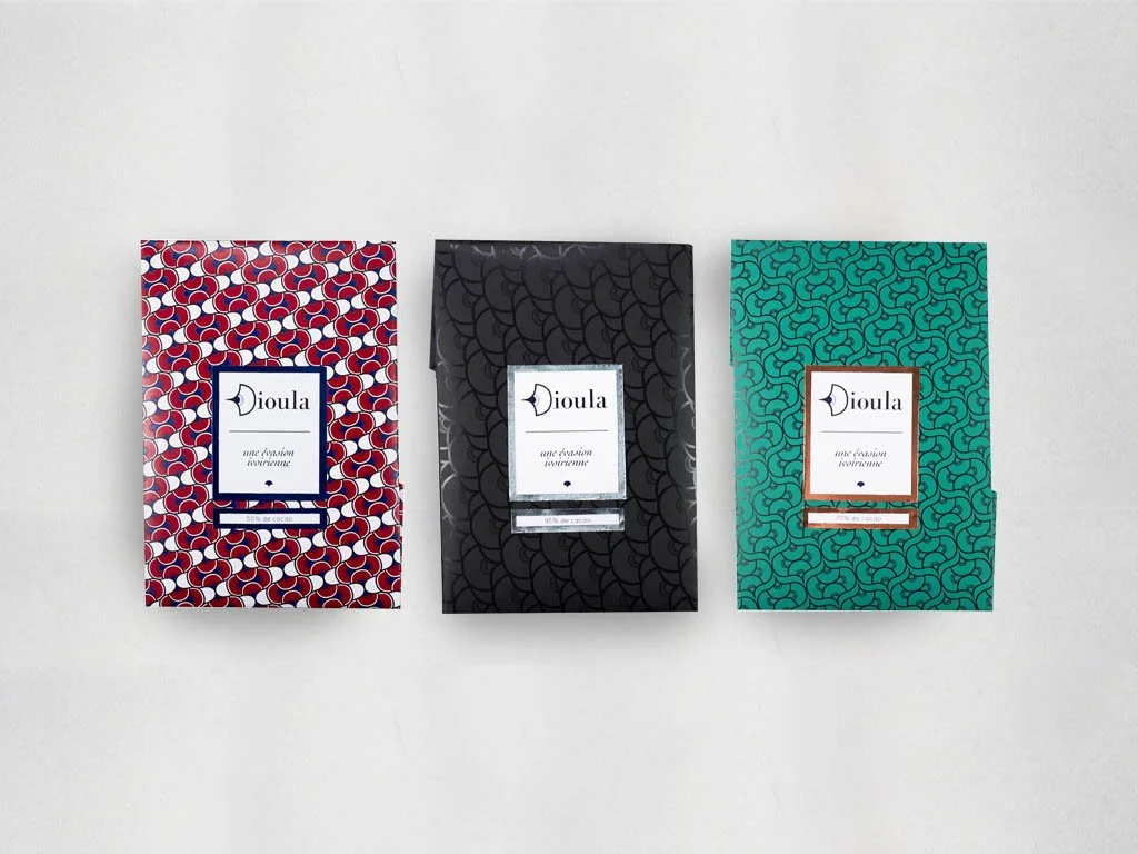 Three patterned chocolate bars in colorful packaging arranged horizontally on a white surface.
