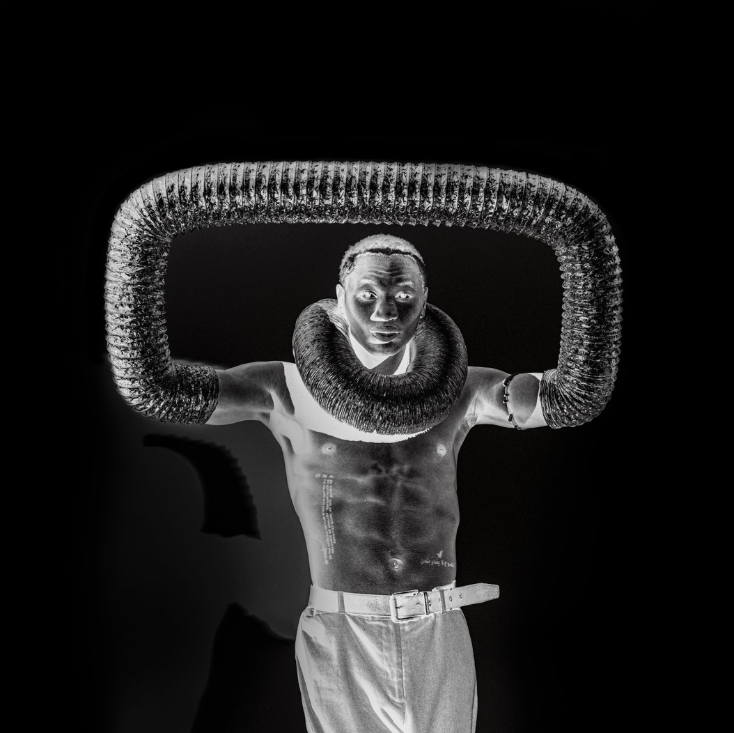 Inversed black and white portrait of a man posing like a statue