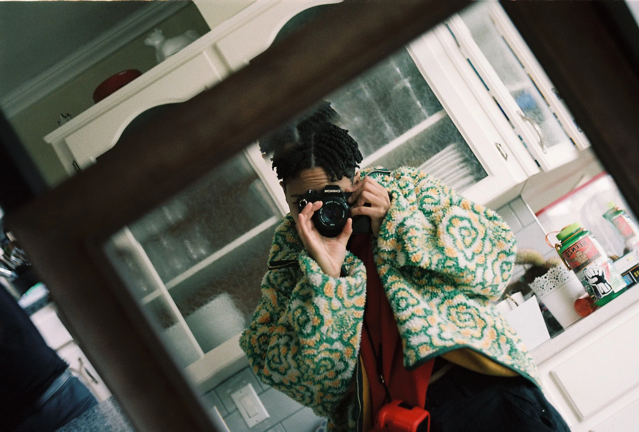 Self-portrait of a person using a titled mirror in what appears to be in a room to photograph themselves
