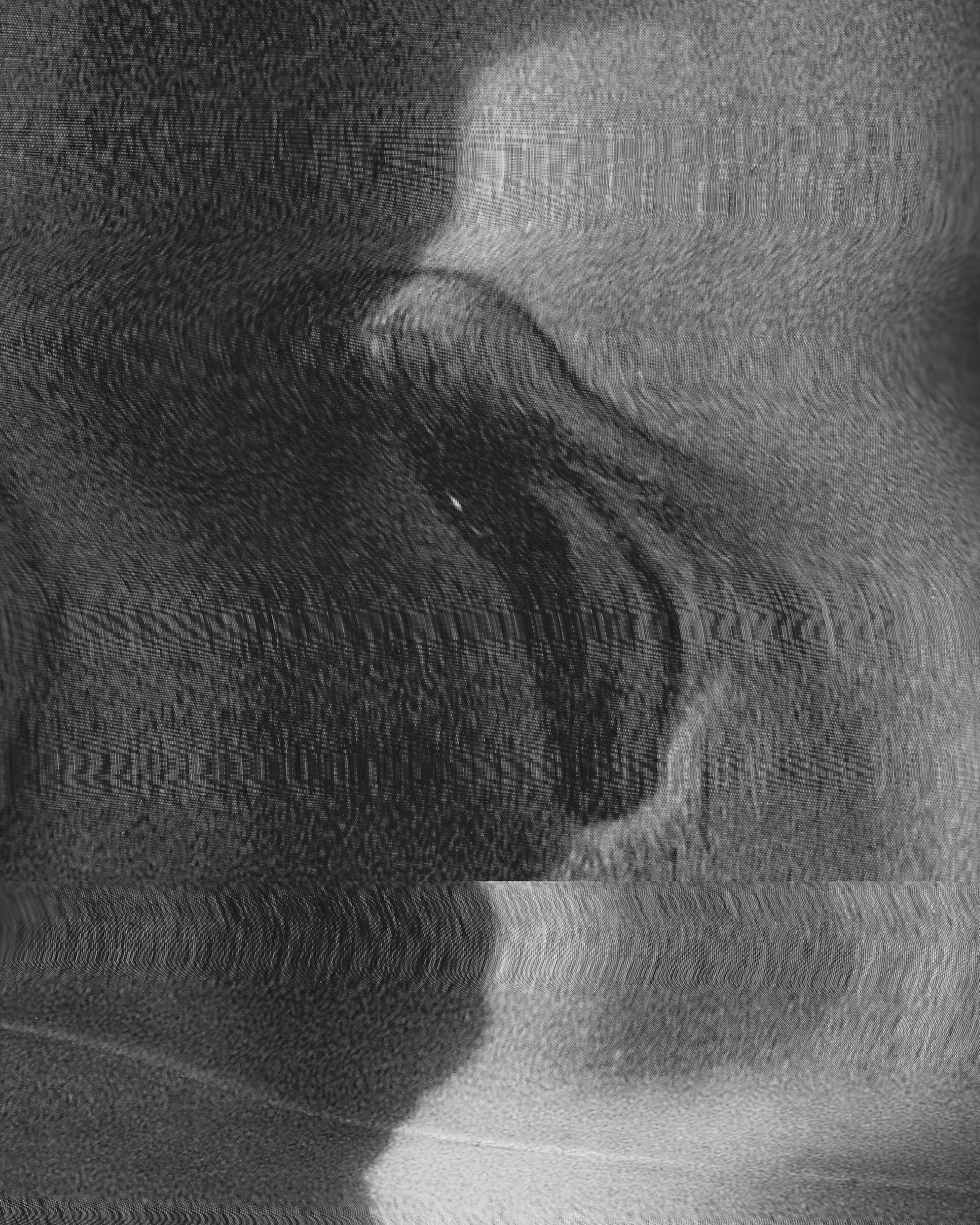 Close-up black and white photograph of a human face, with the eyes closed, showing detailed skin texture and shading.