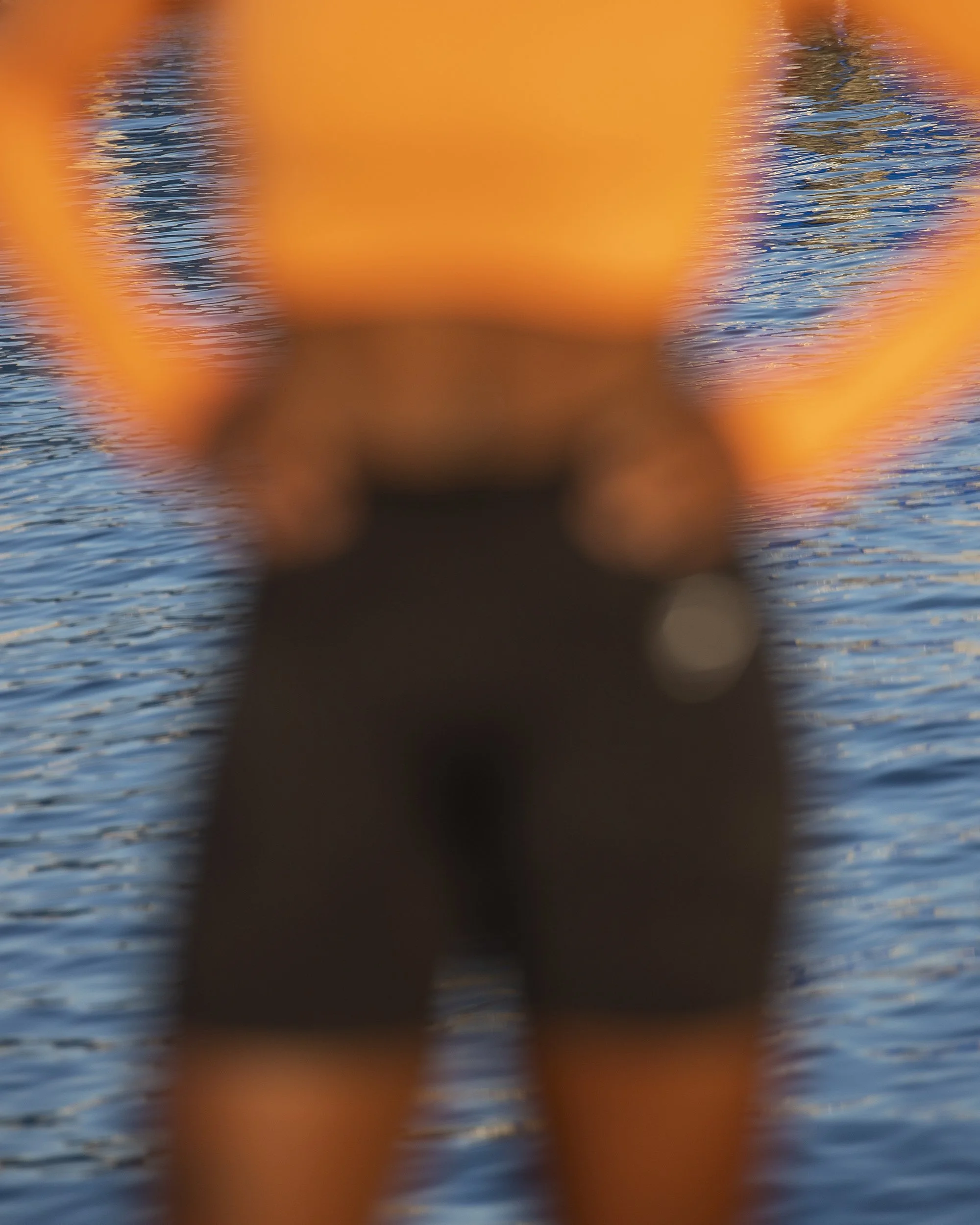 Blurred image of water with small ripples and reflections, with large orange object in center.