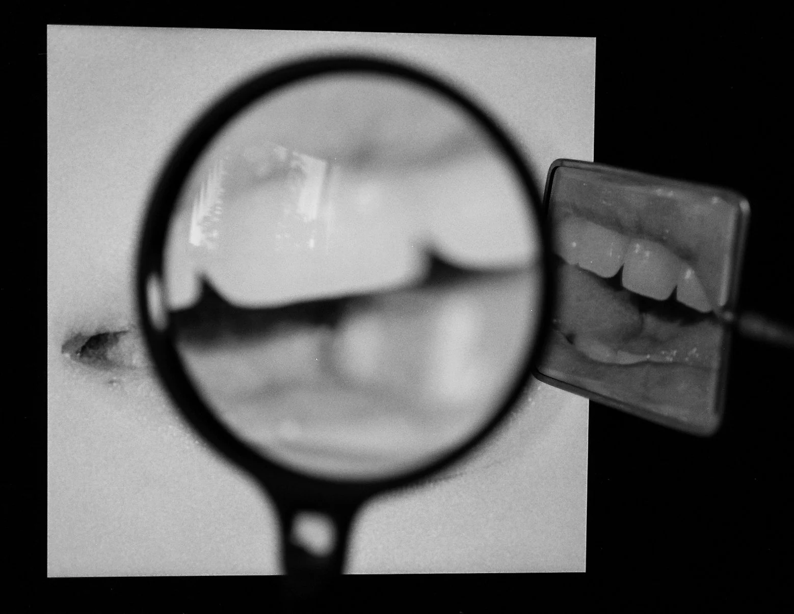 A black and white image of what appears to be a magnifier magnifying an image of lips on a screen