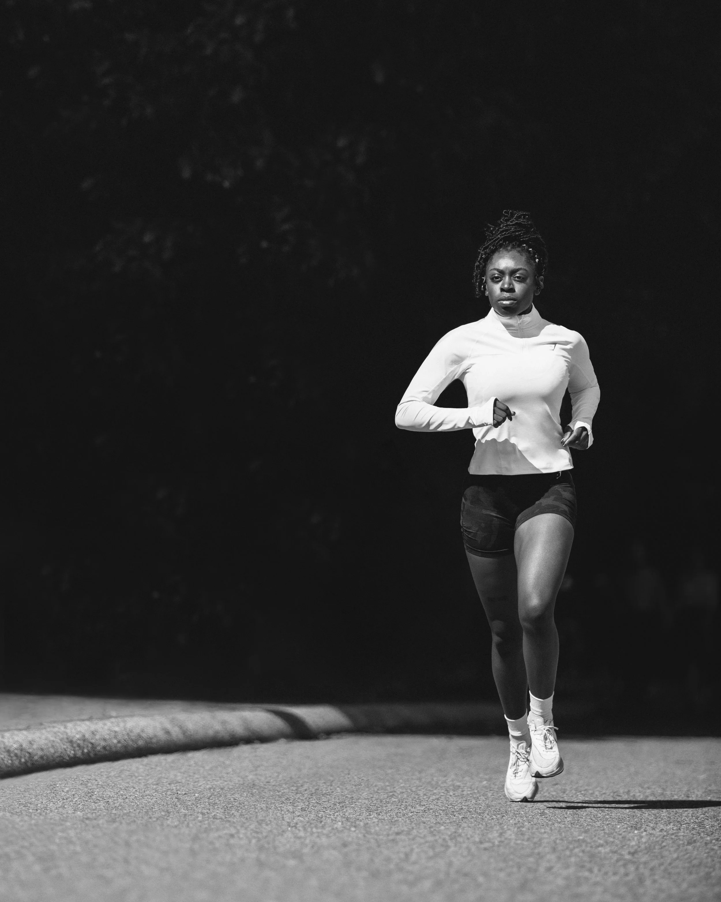 A woman running outdoors at night, wearing athletic clothing, with a focused expression.