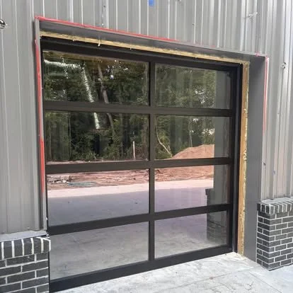 Empty modern garage door with black metal framing and glass panels, surrounded by a metal building exterior.