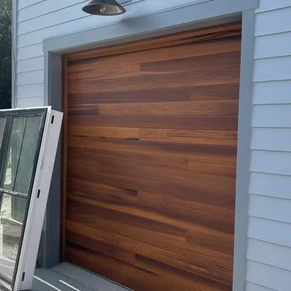 A wooden garage door with horizontal planks, part of a light blue house.
