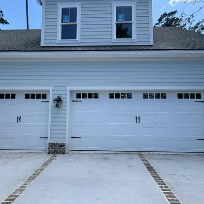 Front view of a house with a three-car garage, white garage doors, and a driveway with brick accents.