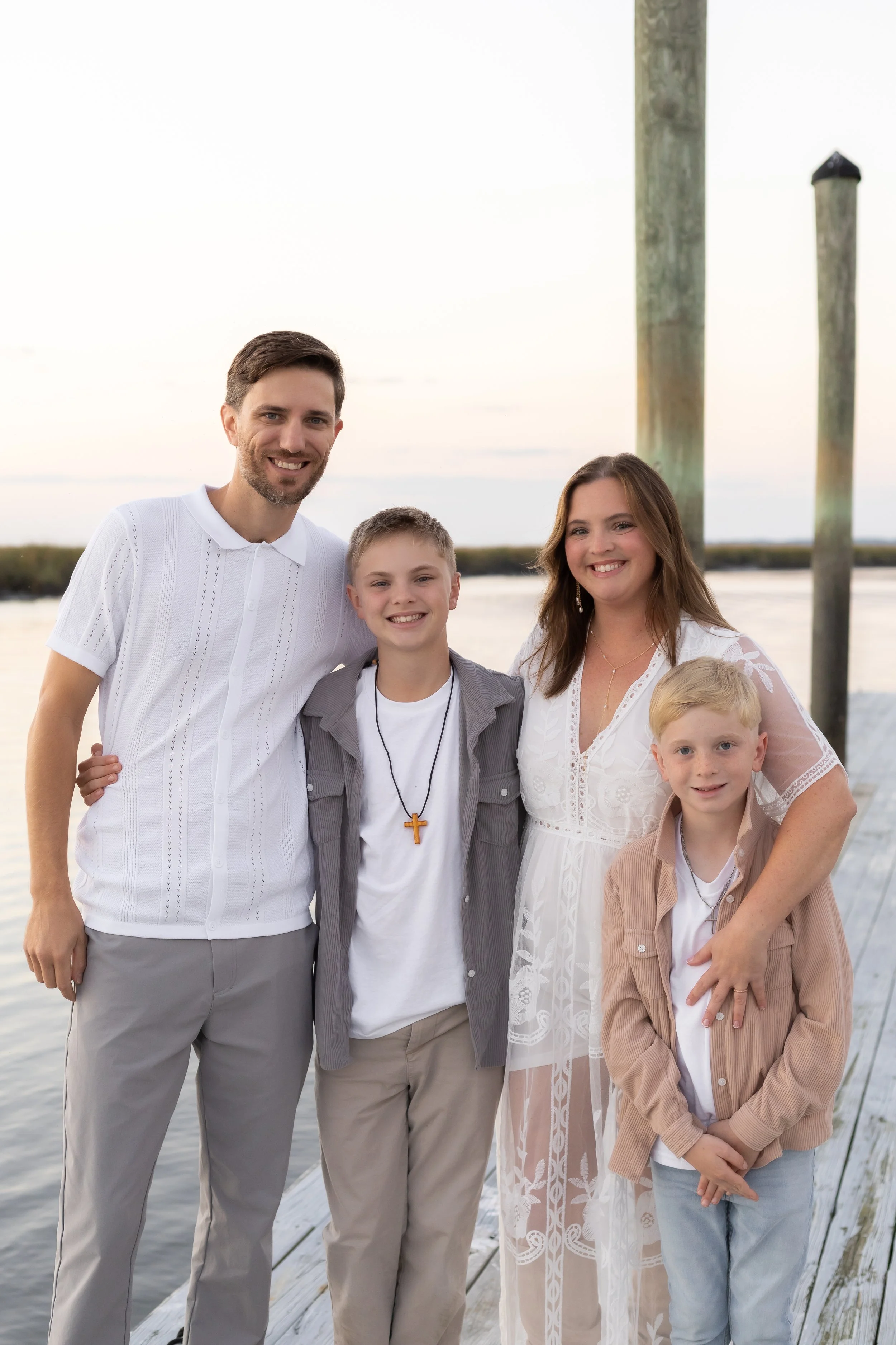 Family photo of the Padgett, The Father, Son, Mother, and Younger Son. Family photo taken at a river bank dock on a light and calm evening night
