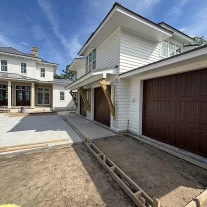Newly constructed residential garage with basic framing and support beams, driveway, and a clear blue sky.