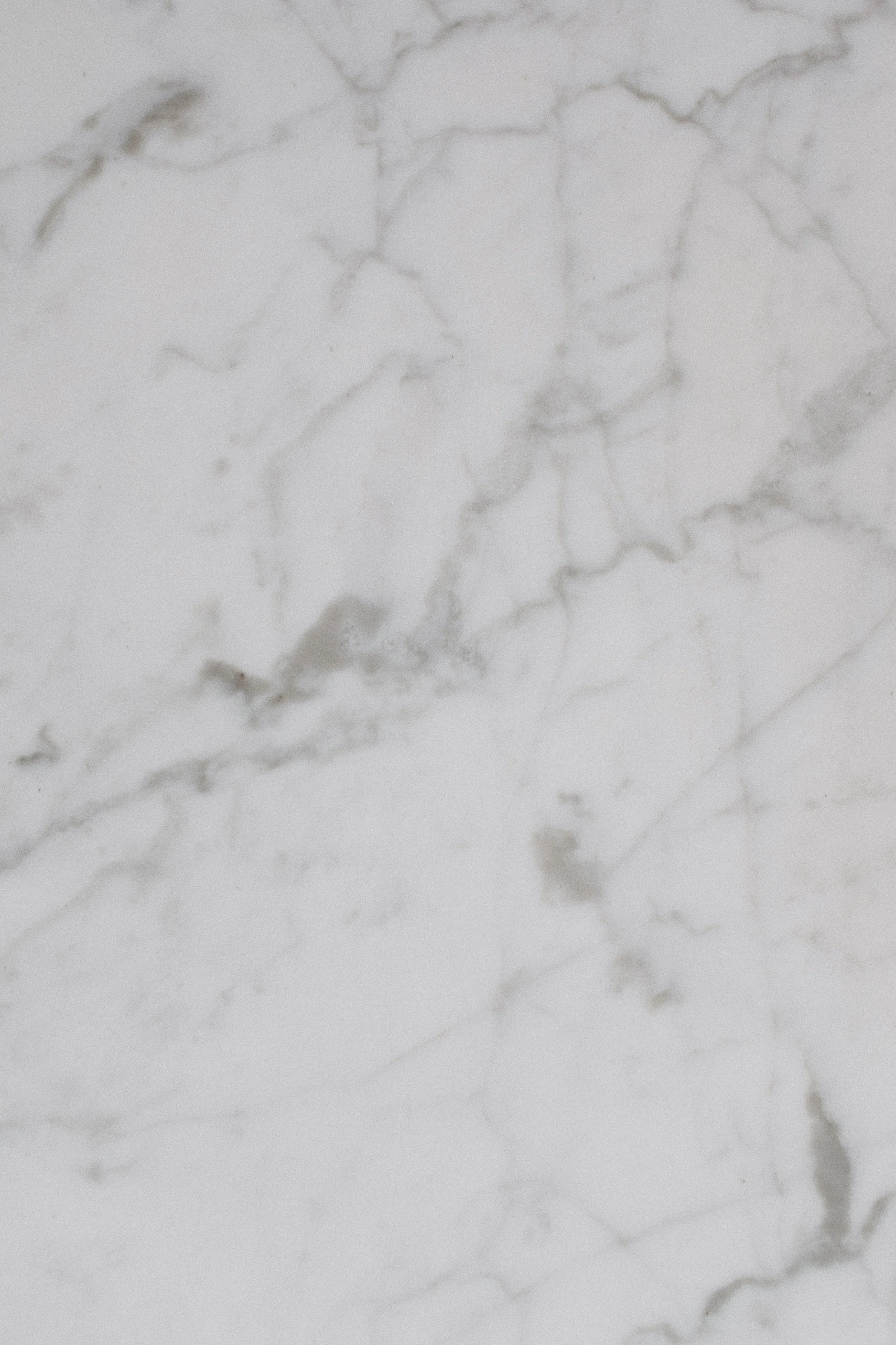 A close-up view of a white marble surface with gray veining.