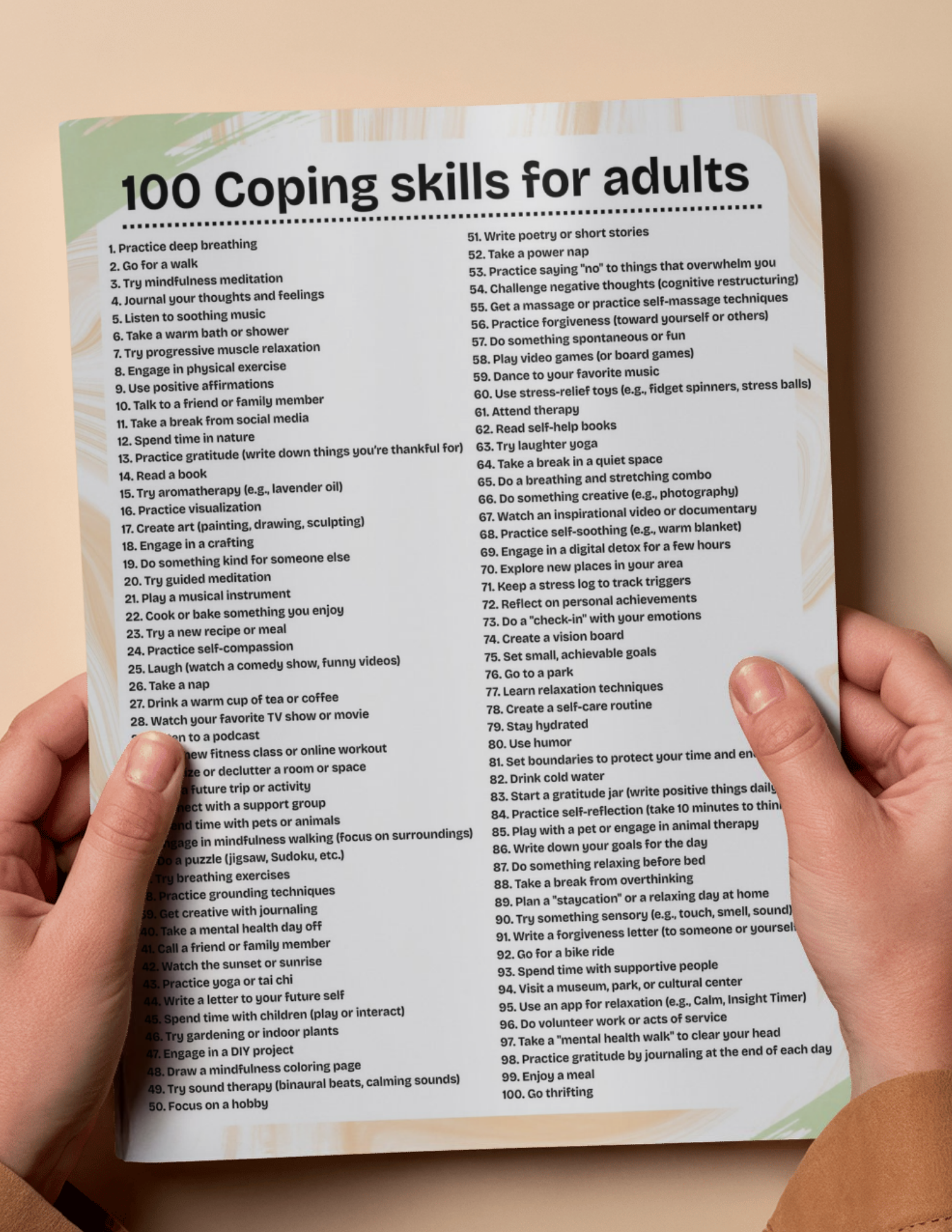 A person holding a list titled '100 Coping skills for adults' with a colorful background. The list includes items such as practicing deep breathing, going for a walk, journaling thoughts, listening to music, taking a warm bath, engaging in physical exercise, practicing mindfulness, creating art, reading, trying aromatherapy, and many more coping strategies.