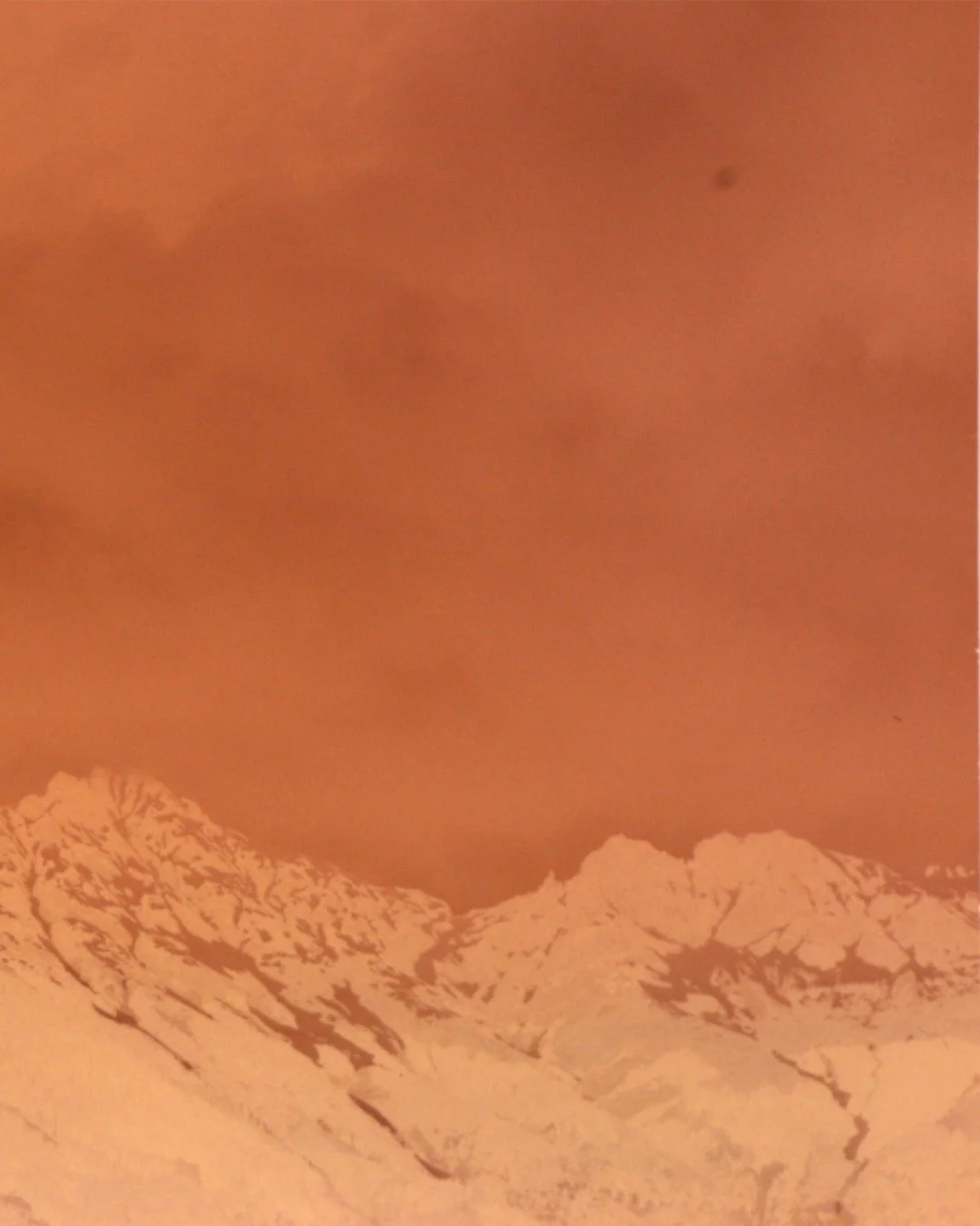 Schneebedeckte Berge bei Sonnenuntergang, orange Himmel.