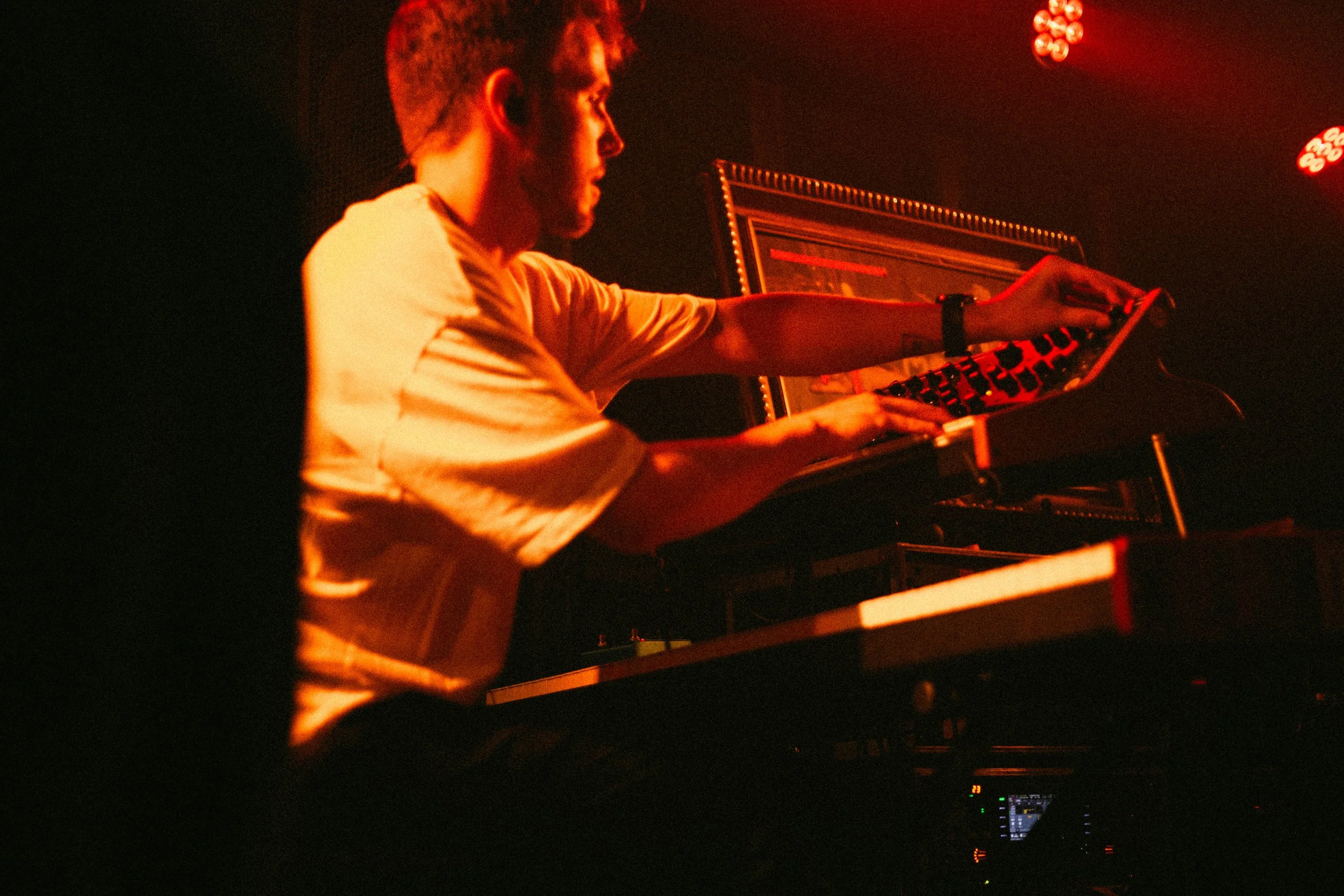 Mann spielt Keyboard in dunklem, rotem Licht bei einem Konzert.