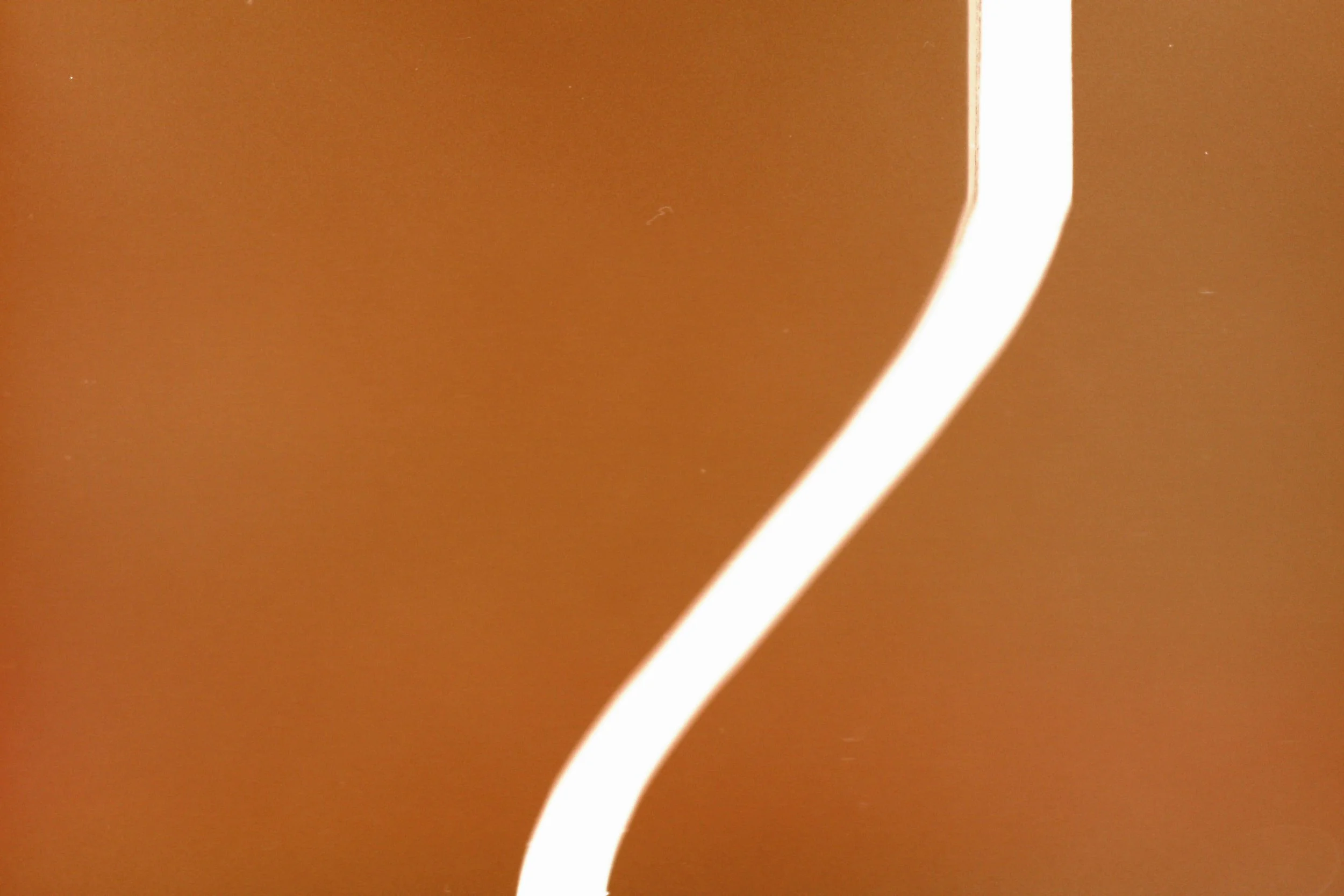 Nahaufnahme eines weißen Lichtstreifens vor einem orange-braunen Hintergrund.