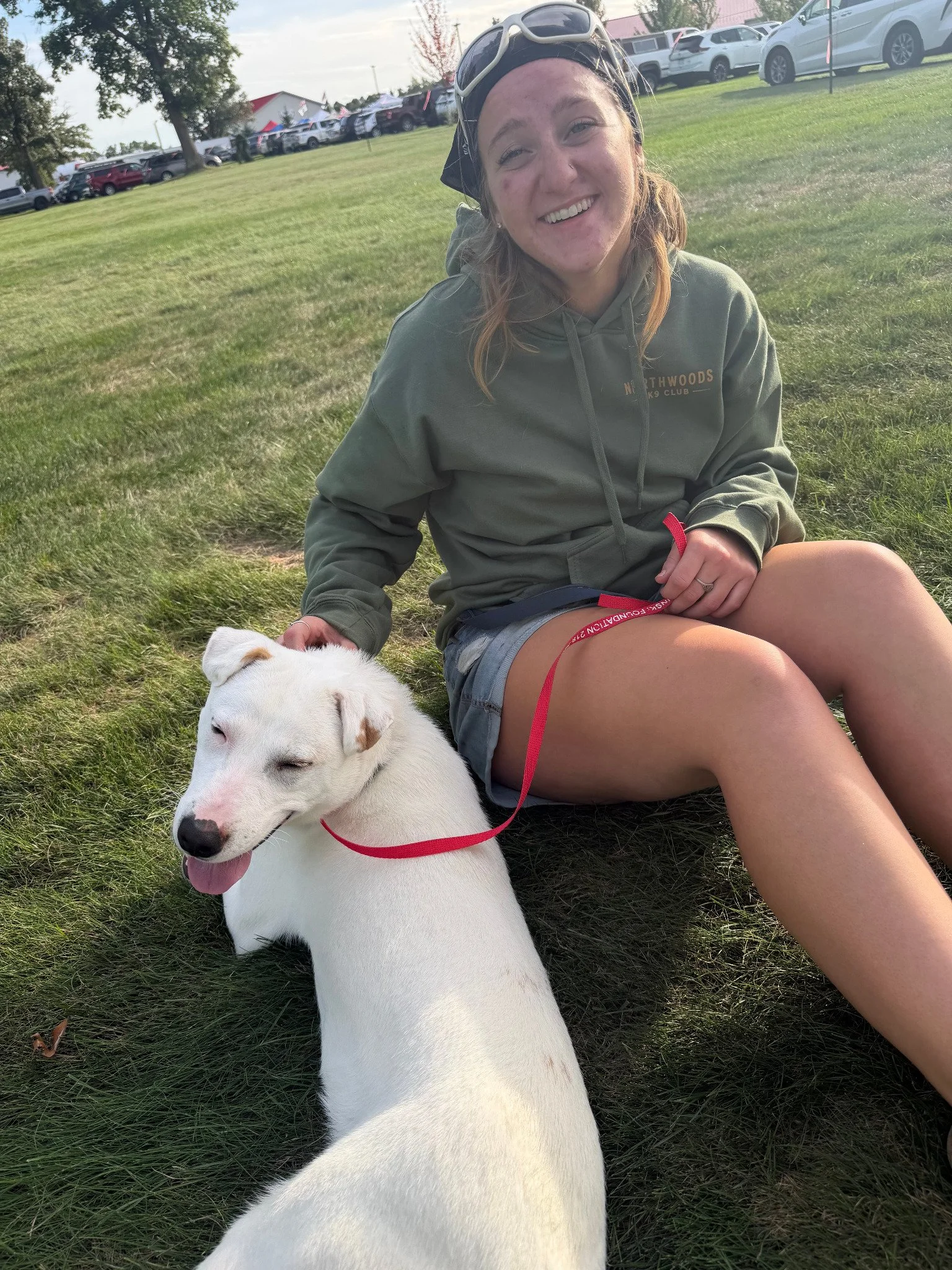 Morgan Hagel, Lead Groomer at Northwoods K9 Club, sitting outdoors with a dog.