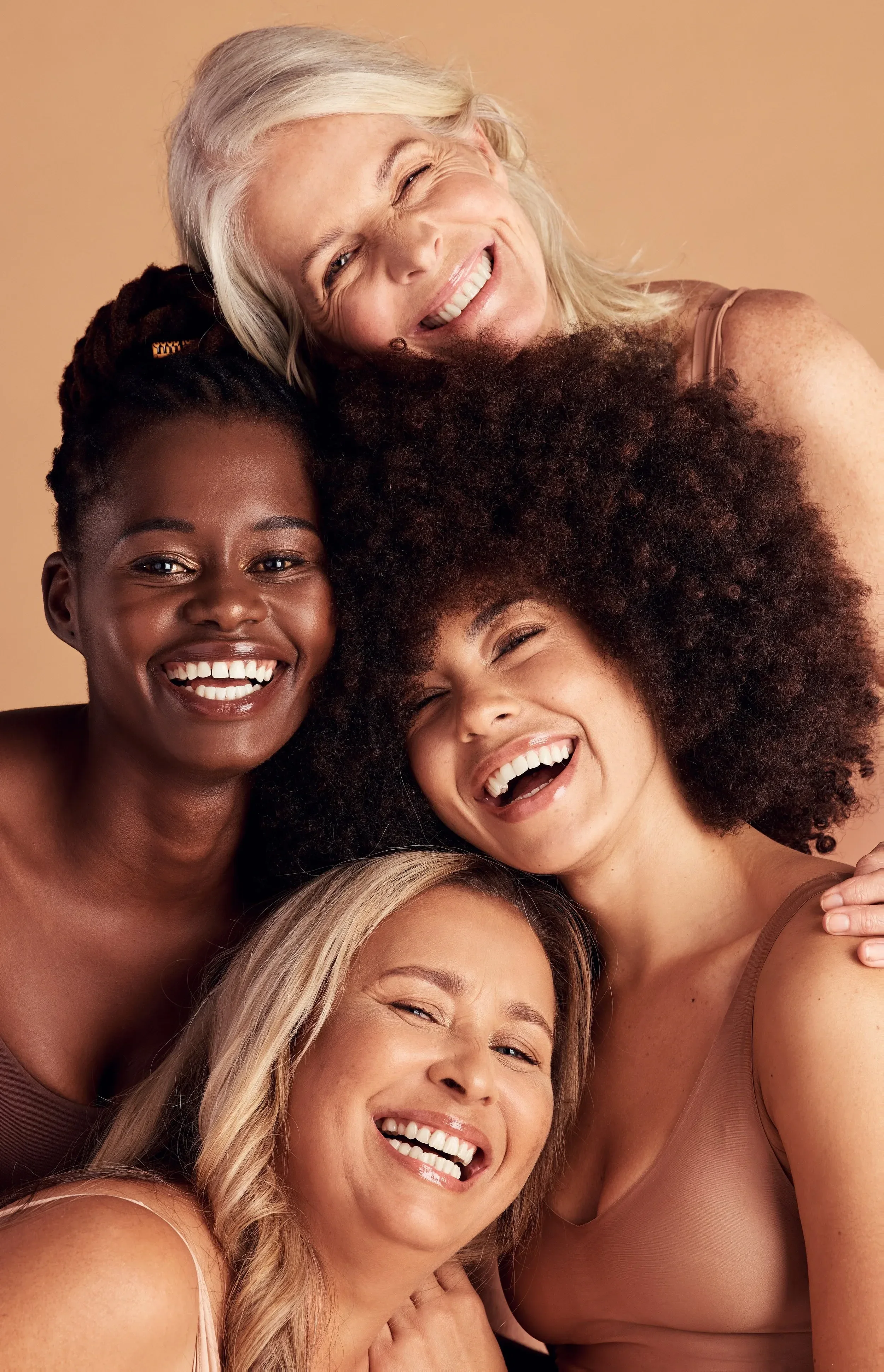 Group of diverse women laughing and smiling closely together, showing joy and friendship.