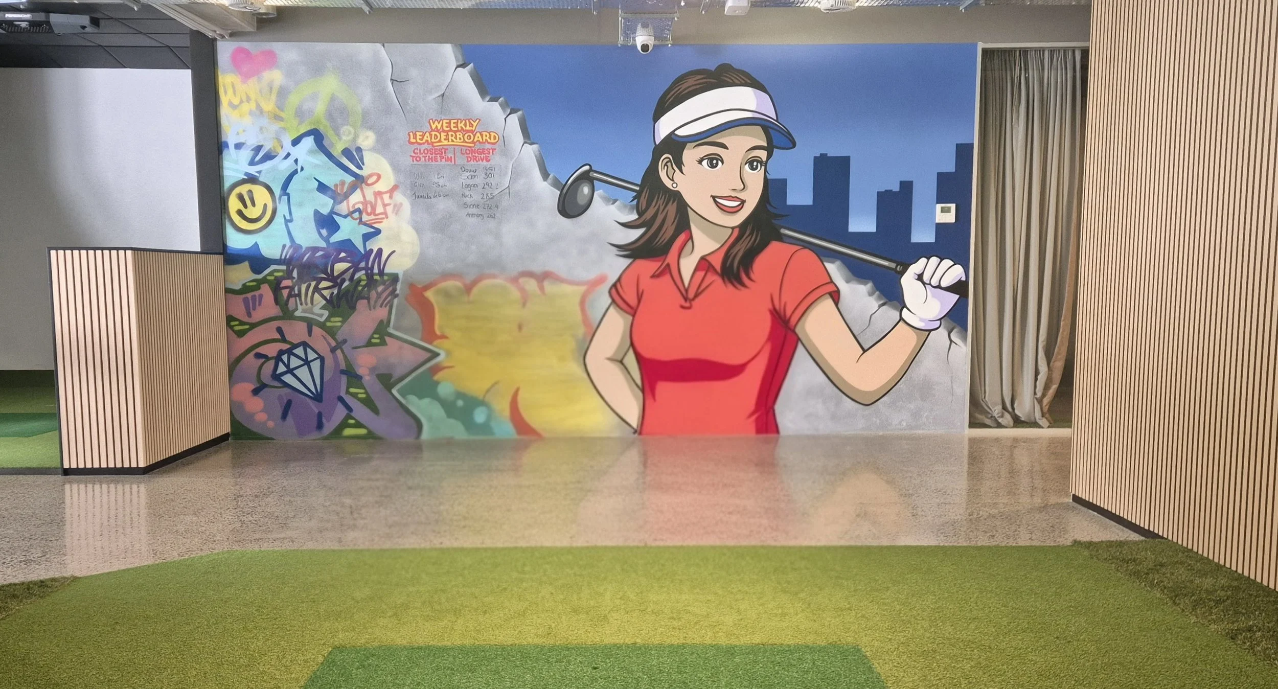 A colorful mural featuring a smiling woman in a red shirt and white visor, holding a golf club, with city skyline and graffiti art in the background.