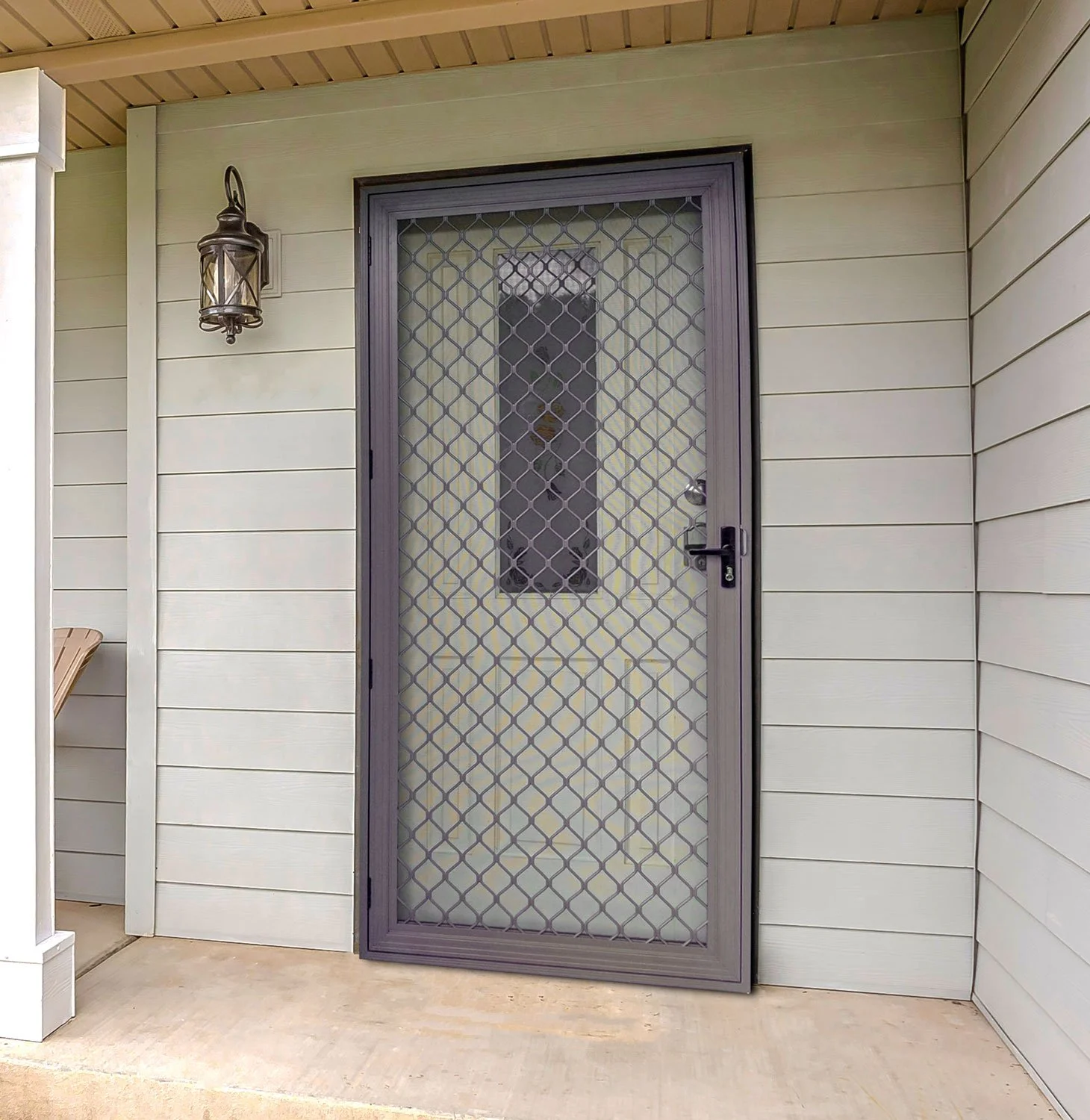 Front porch with a decorative security screen door, gray siding, and wall-mounted lantern