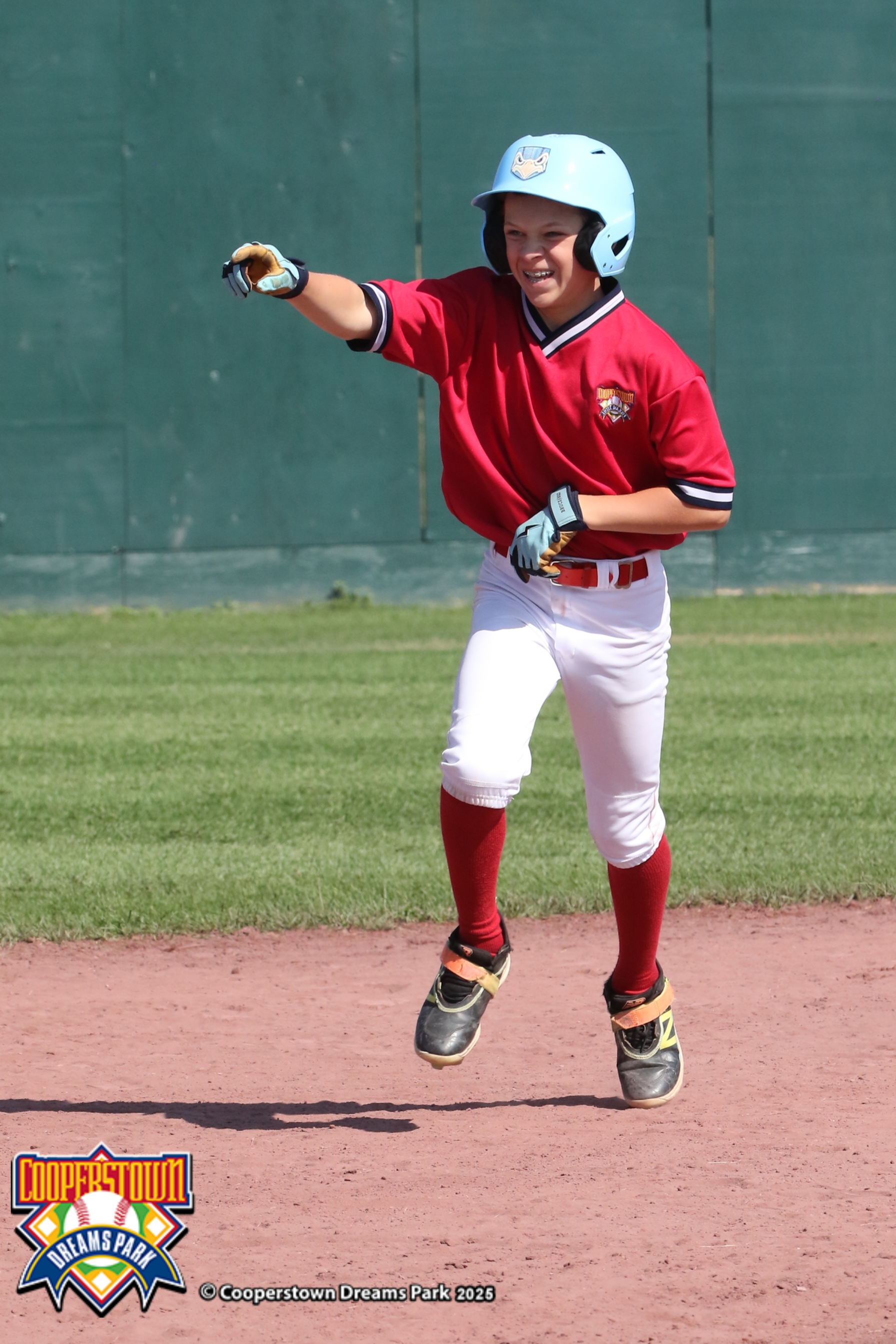 Youth baseball player celebrating at Cooperstown Dreams Park after a successful at-bat.