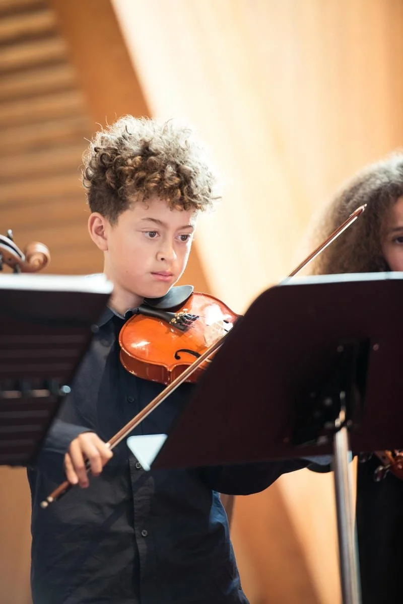 Young violin student performing at a music recital