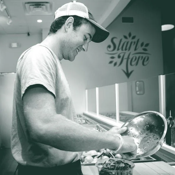 A chef in a hat skillfully prepares food, highlighting Verde's dedication to fresh, healthy meals in Charleston, SC.