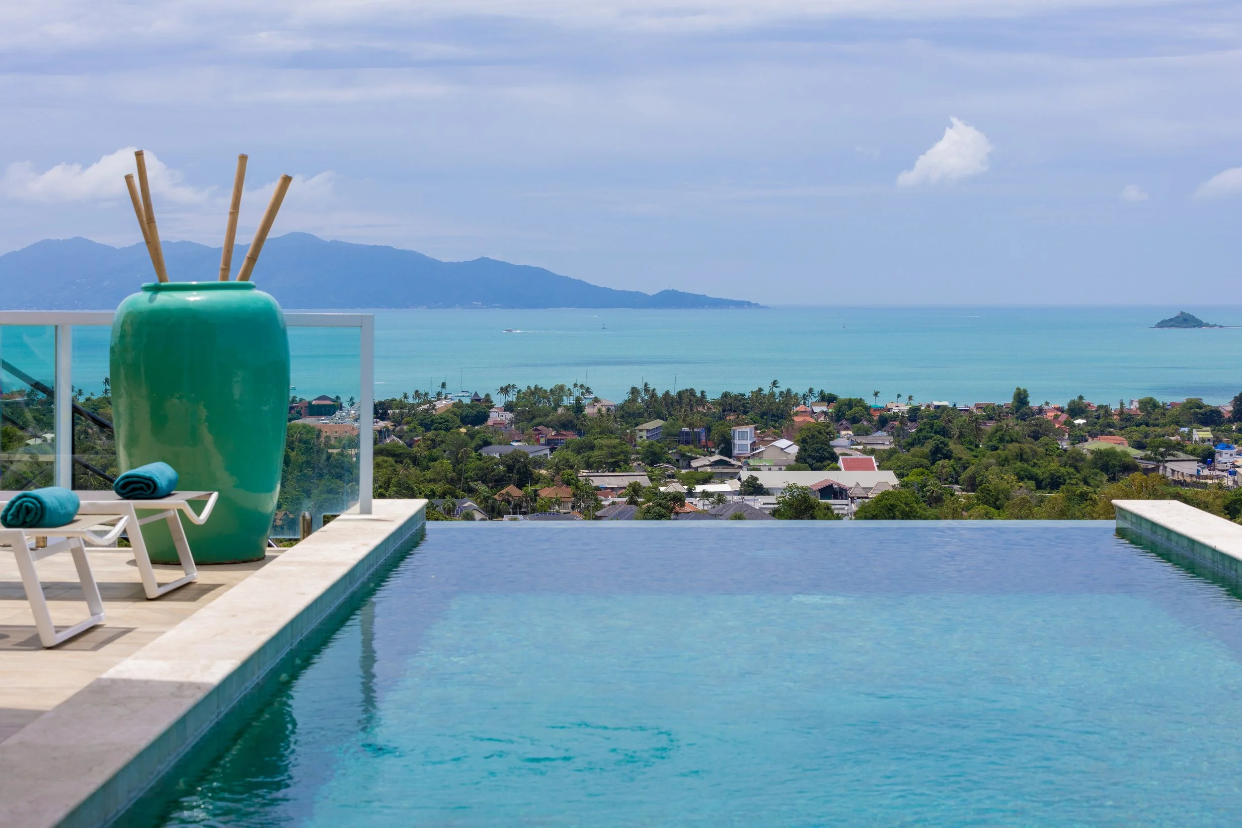 Swimming pool with a view of the ocean and mountains in the distance.