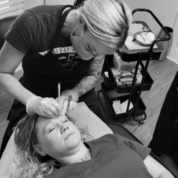A woman receiving a cosmetic or medical procedure on her face in a clinical setting.