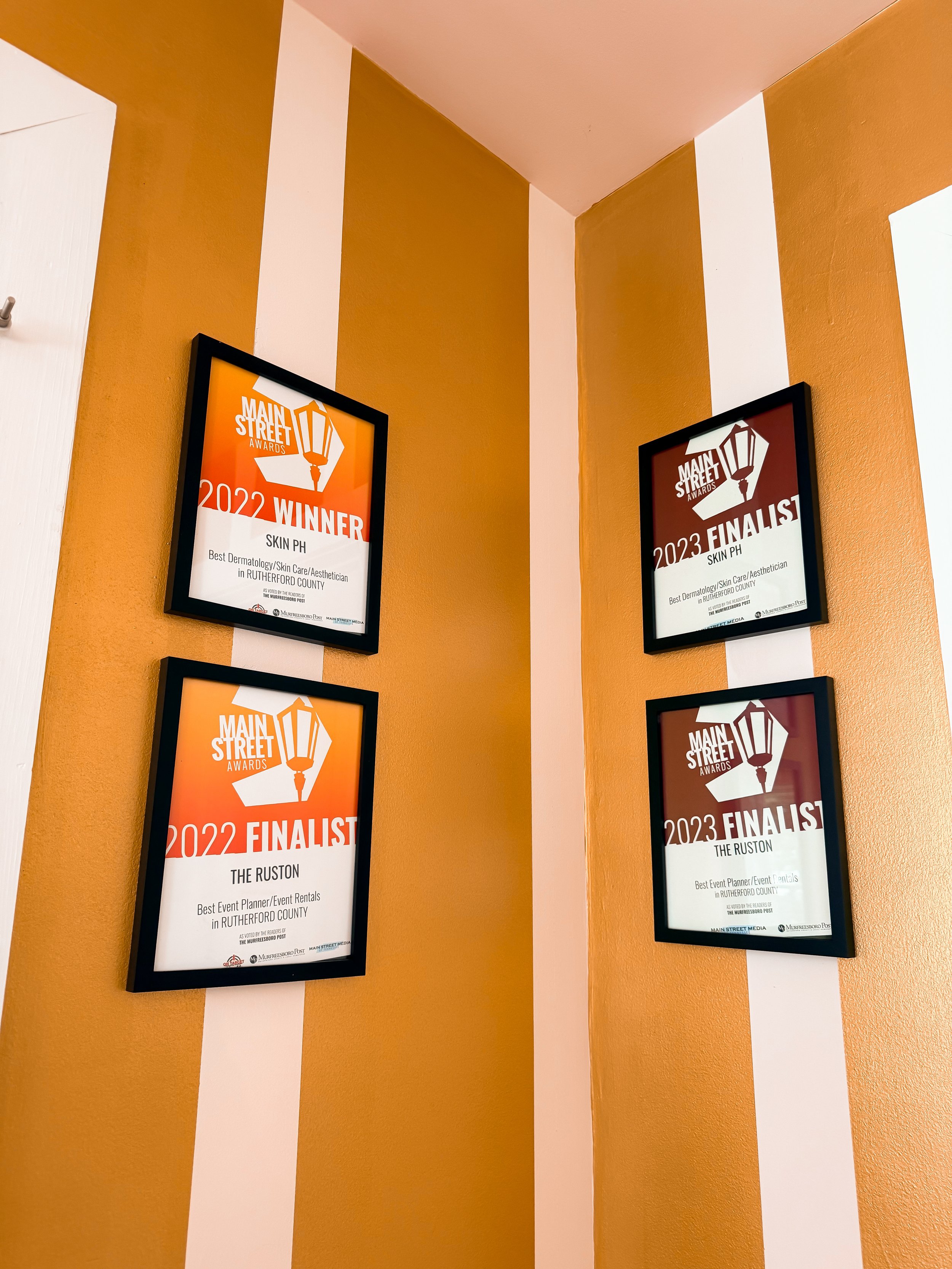 Framed awards on a wall for Main Street Awards, 2022 Winner and 2023 Finalist for Skin PH in Rutherford County, presented by The Murfreesboro Post.