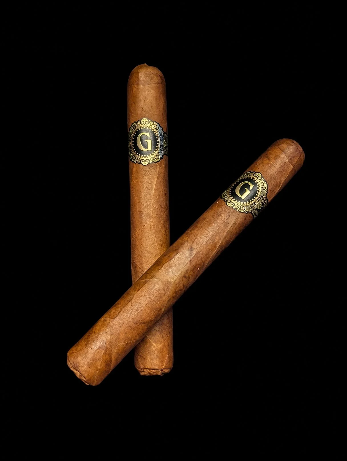 Two cigars with black and gold labels against a black background.
