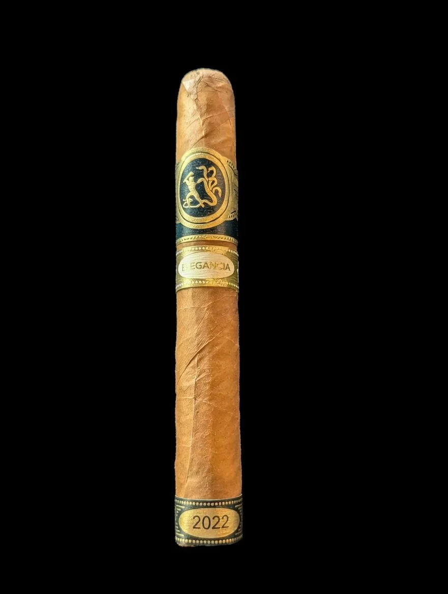 Single cigar with black and gold band and a blue label, set against a black background.
