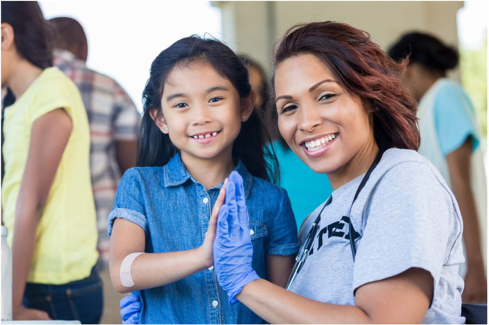 A young girl and a healthcare worker giving each other a high five in a clinic or medical setting.