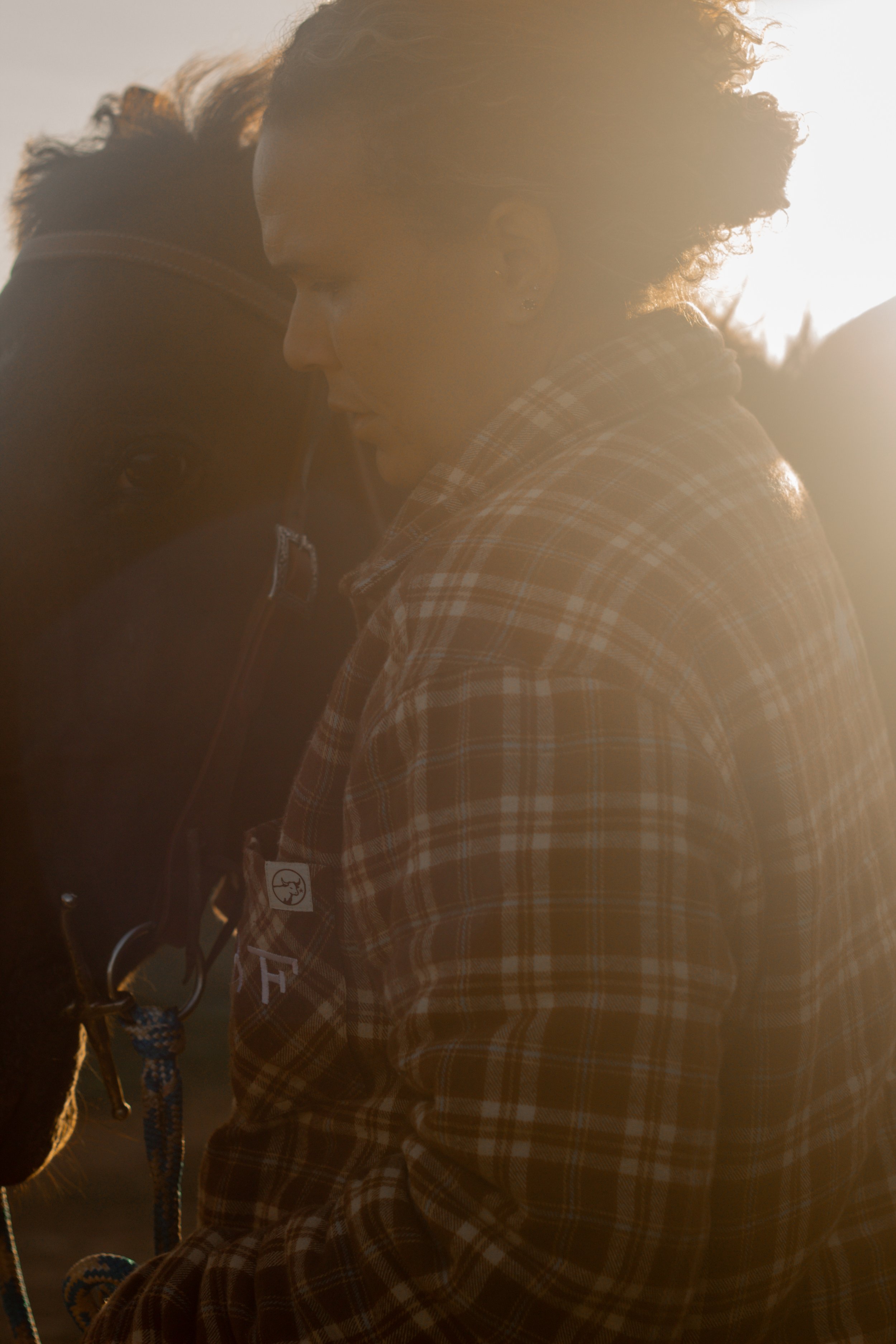Two people embracing each other closely in a warm outdoor setting, with sunlight creating a glow around them.