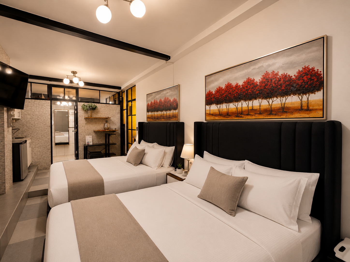 Two neatly made beds in a modern hotel room with black headboards, beige bed runners, and pillows, decorated with paintings of red trees on the wall. Nicely lit with bedside lamps and ceiling lights, with a small table and shelf at the back of the room.