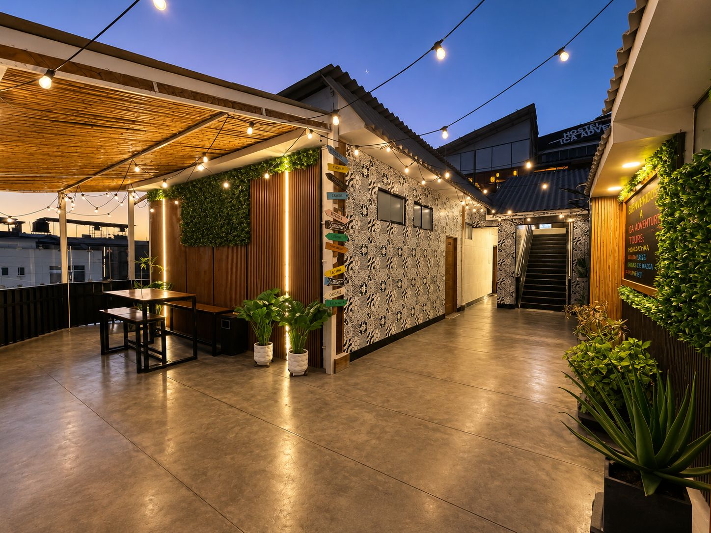 Rooftop outdoor terrace with string lights, potted plants, and decorative walls at dusk.