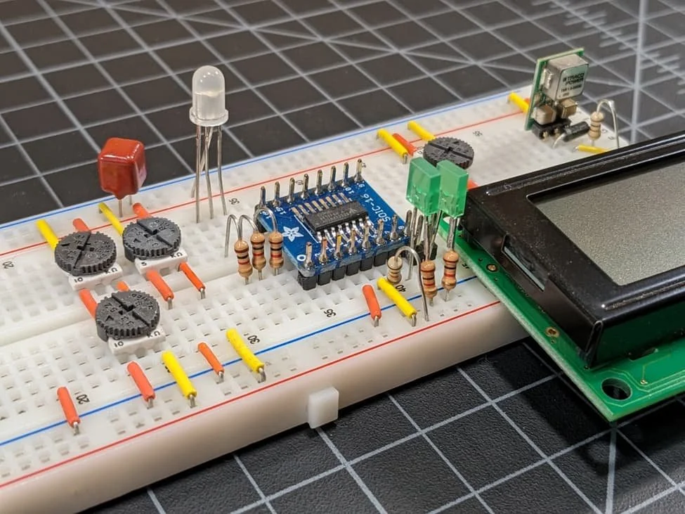 Breadboard with electronic components, resistors, potentiometers, a microcontroller, a LED, and a small display connected.