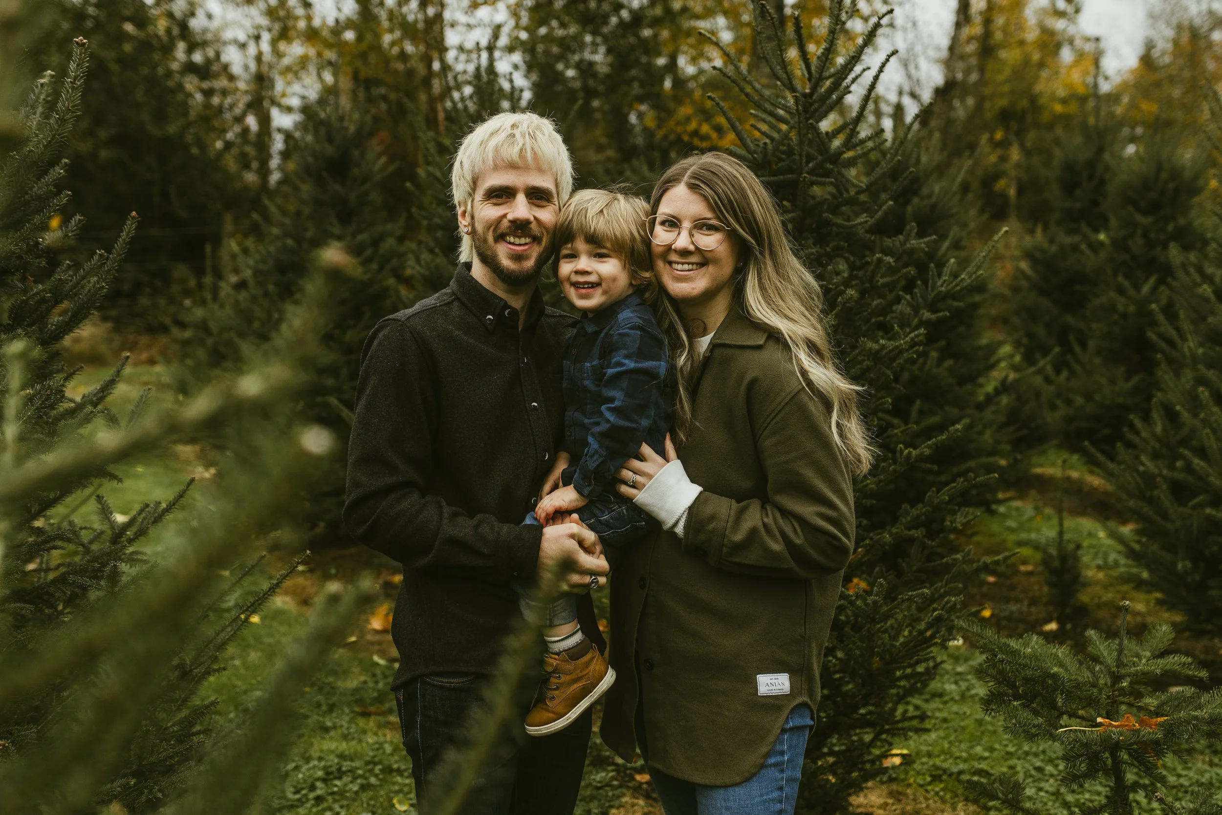 Family of three among the evergreens on an autumn afternoon