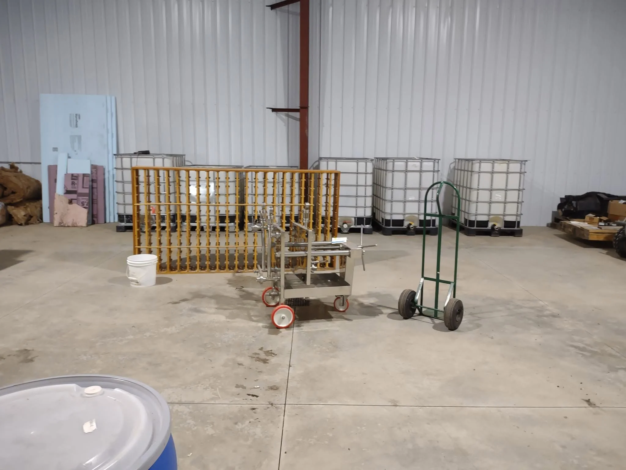 Storage area with white wall, various carts, pallets, and containers.