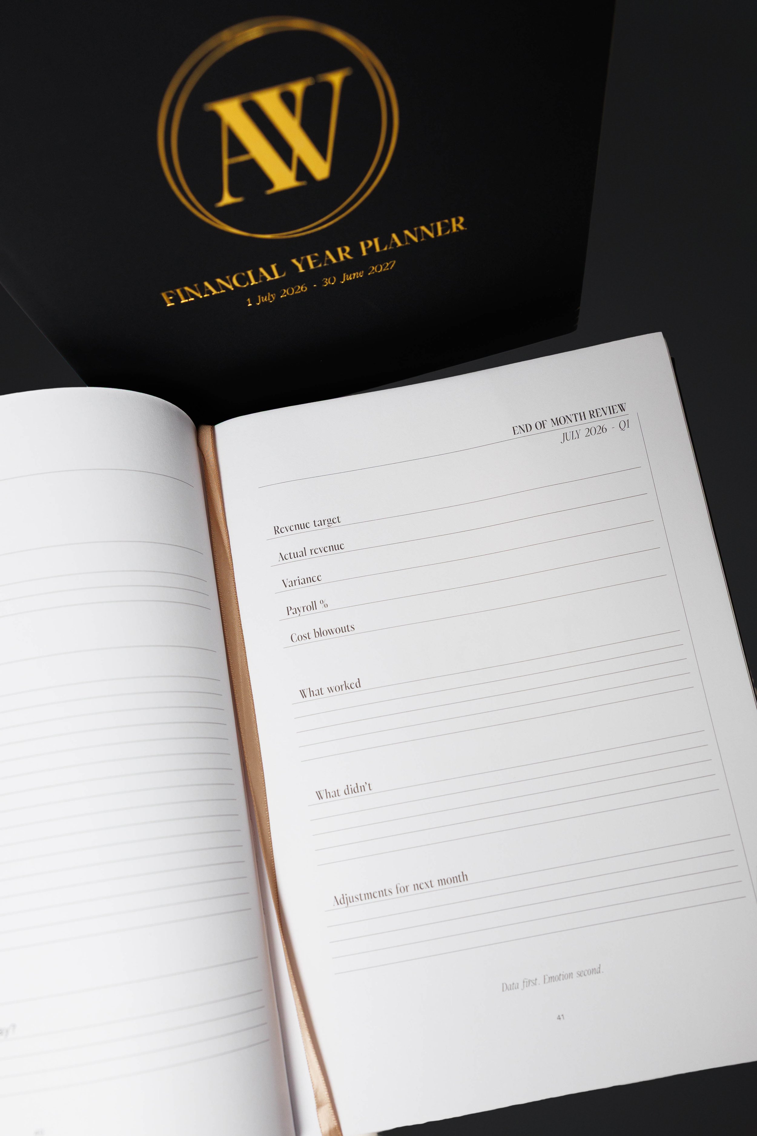 Open workbook and black folder with gold logo and text for a financial year planner covering July 2026 to June 2027.