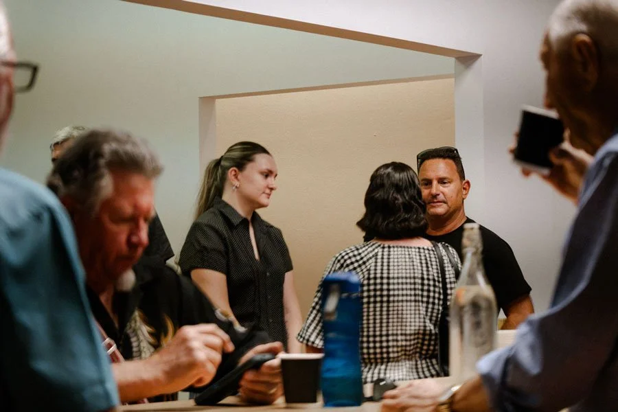 People gathered around a countertop in a casual setting, engaging in conversation.