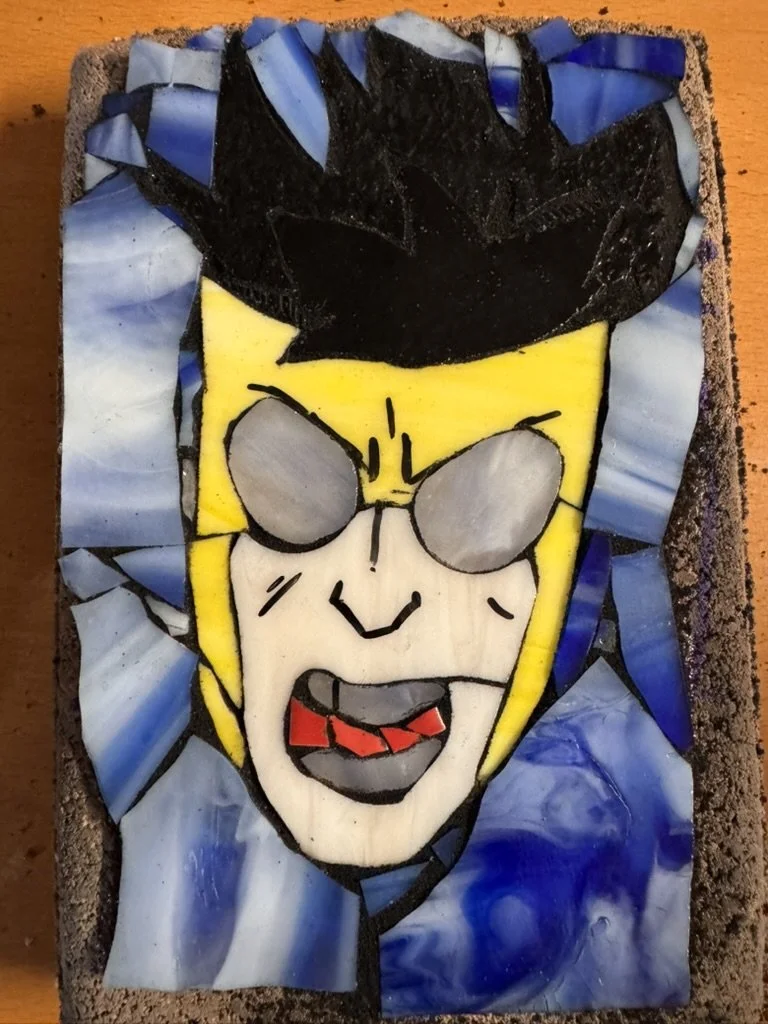 A mosaic artwork of a cartoon character with black spiky hair, yellow face, gray sunglasses, and an open mouth with a red tongue, set on a textured background.