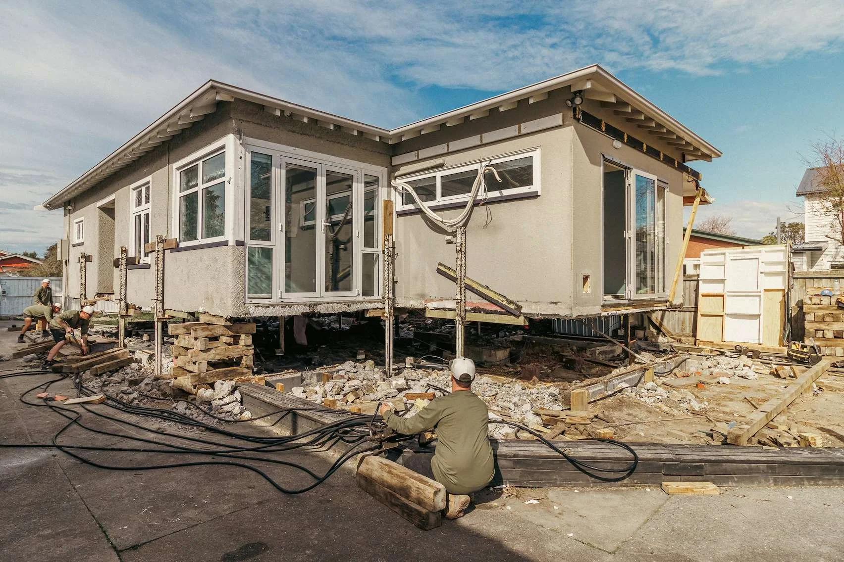 Greenway Construction crew operating hydraulic jacks to lift and prepare a classic character house for relocation to North Canterbury