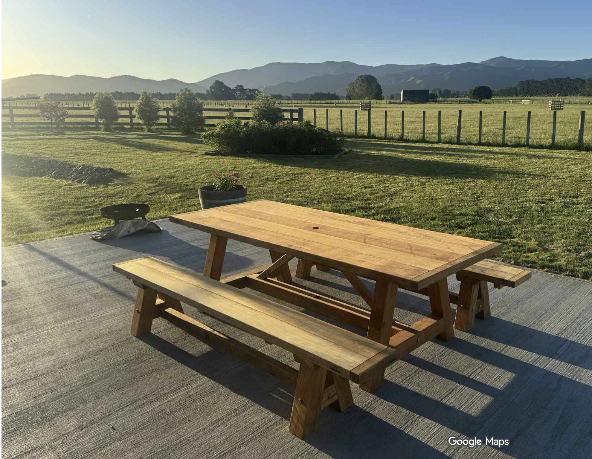 2.7 metre Macrocarpa outdoor dining table with matching benches in a high-wind outdoor area.