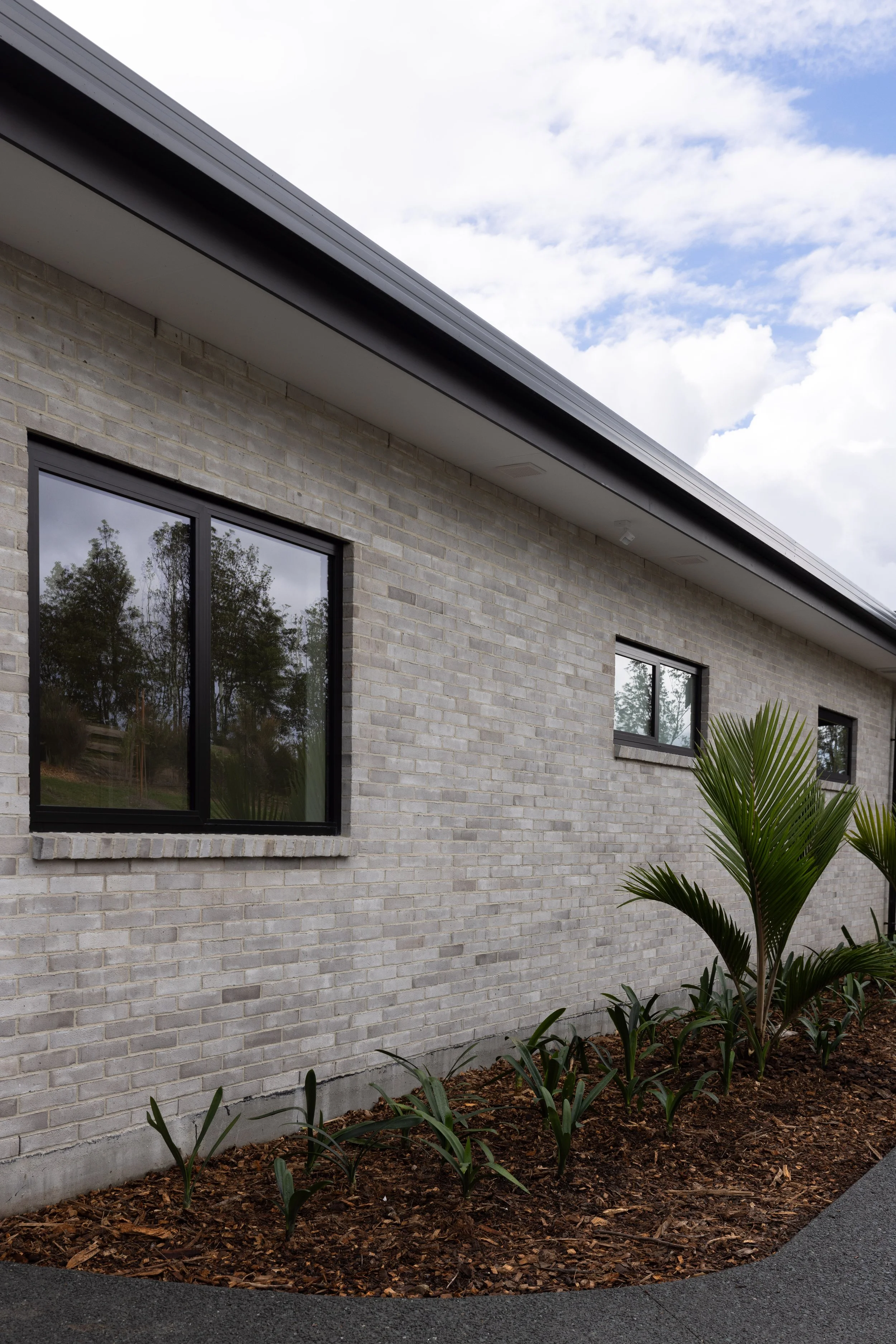 Side view of completed Mangawhai home showing contemporary exterior cladding and windows.