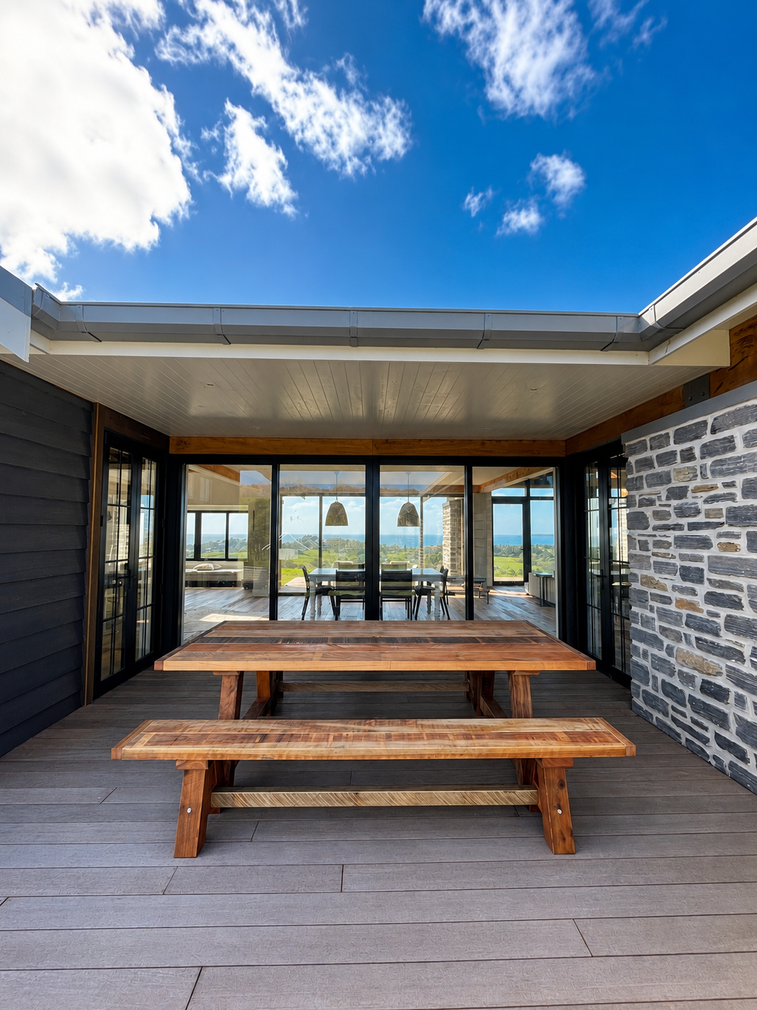 Macrocarpa dining table and matching bench seats under a covered outdoor area.